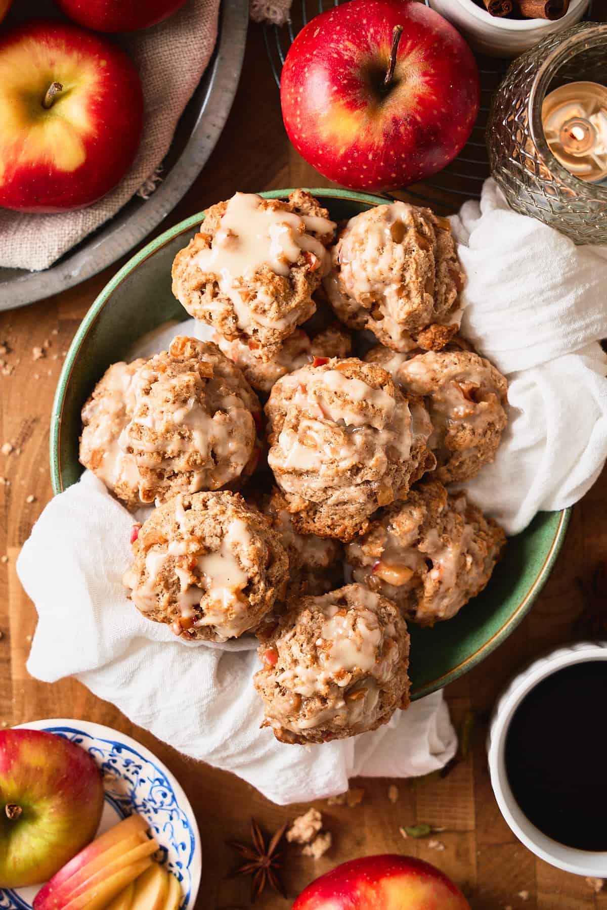 Flatlay photo of a green bowl filled witb a white linen, and a bunch of apple cinnamon drop biscuits.