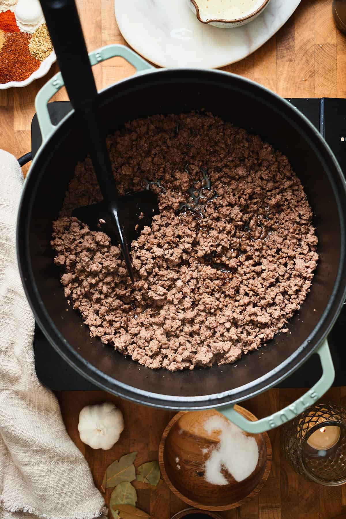 Browned ground beef crumbles in a Dutch oven with a spatula.