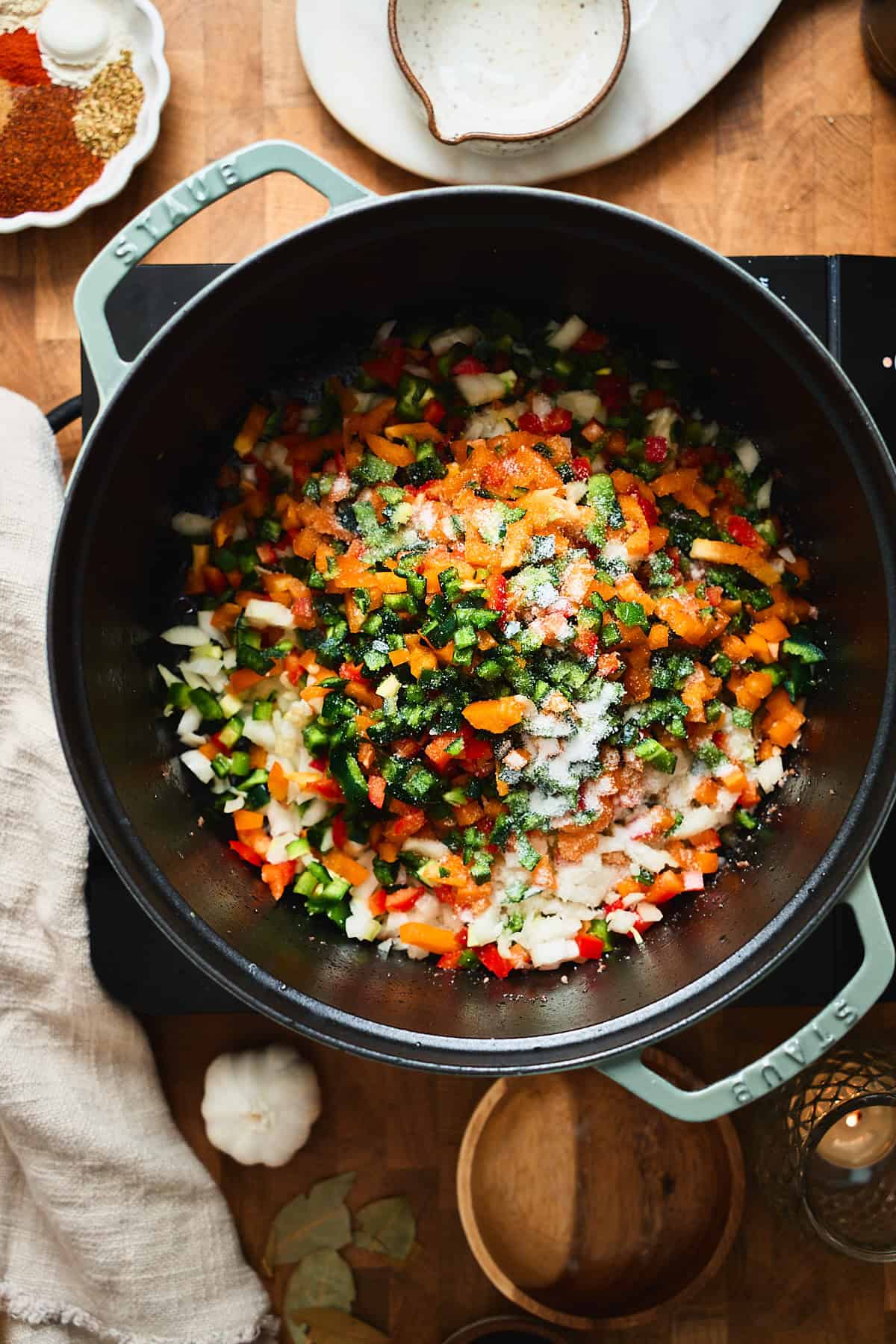 Diced bell peppers, poblanos, jalapeños, and onions in a Dutch oven with salt.