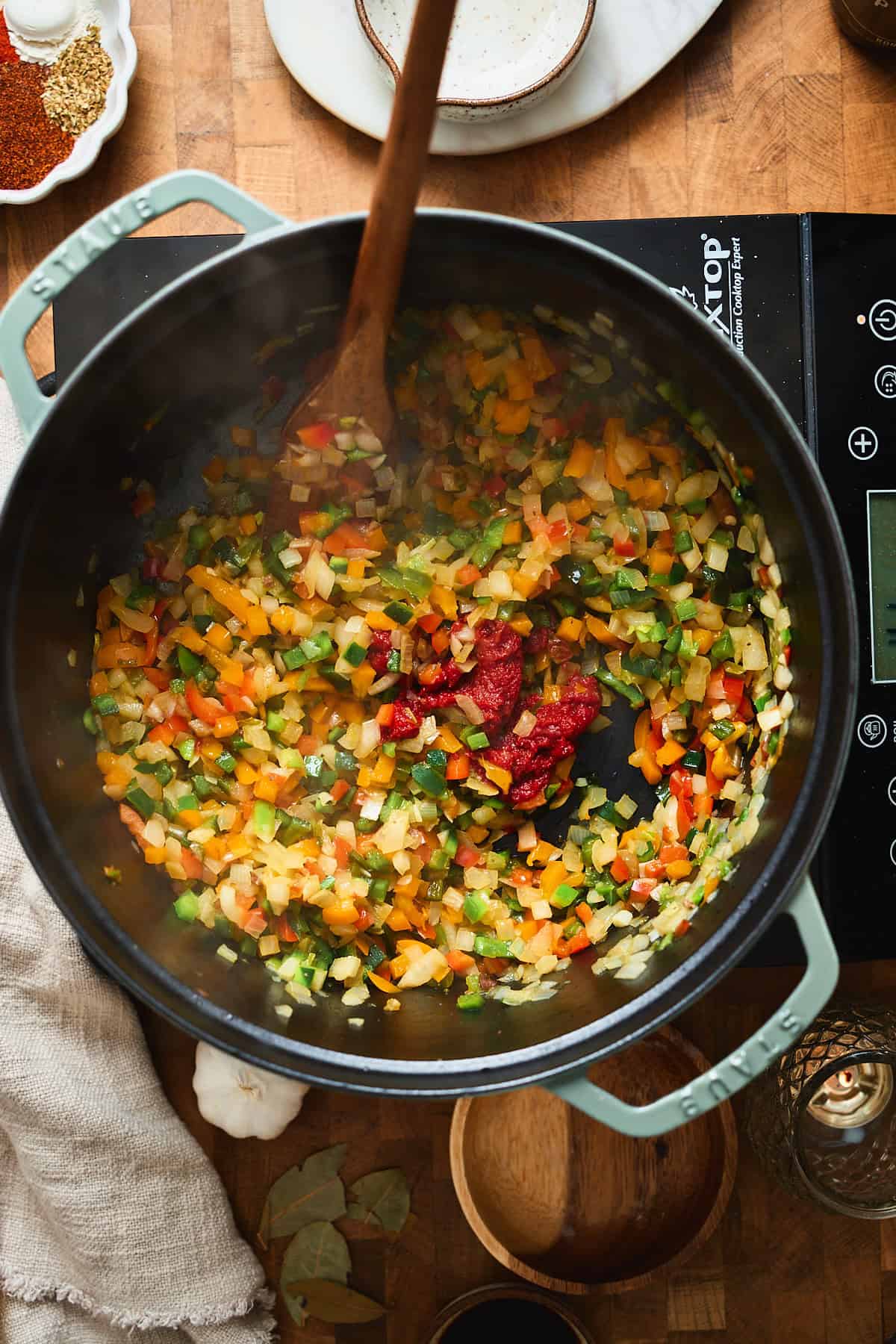 Tomato paste added to softened peppers and onions in a Dutch oven.