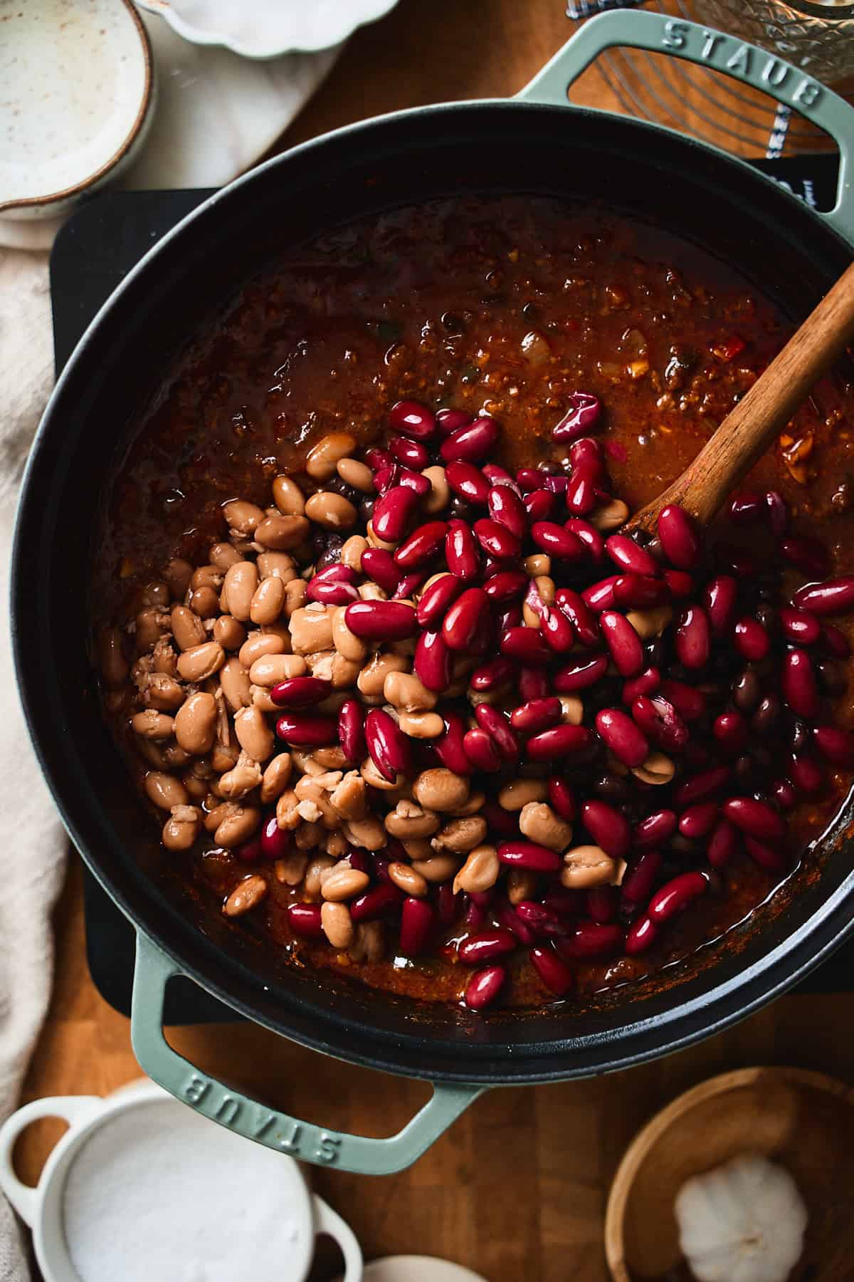 Kidney beans and pinto beans added to beer chili in a Dutch oven.