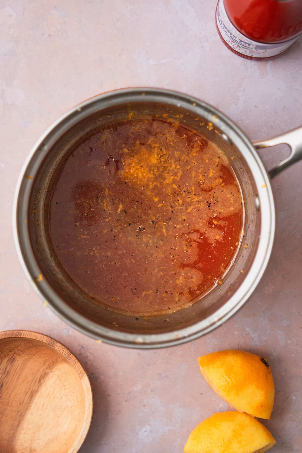 Lemon zest and juice added to a hot honey butter sauce in a saucepan.