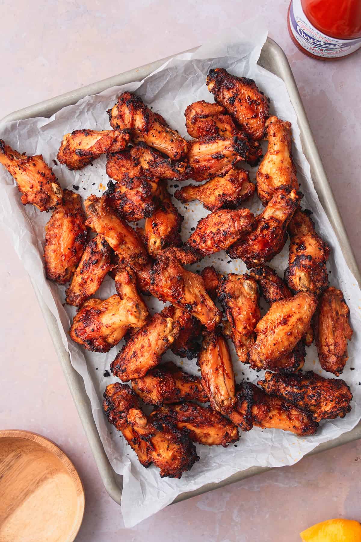 Cooked and crispy chicken wings on a parchment lined baking sheet.