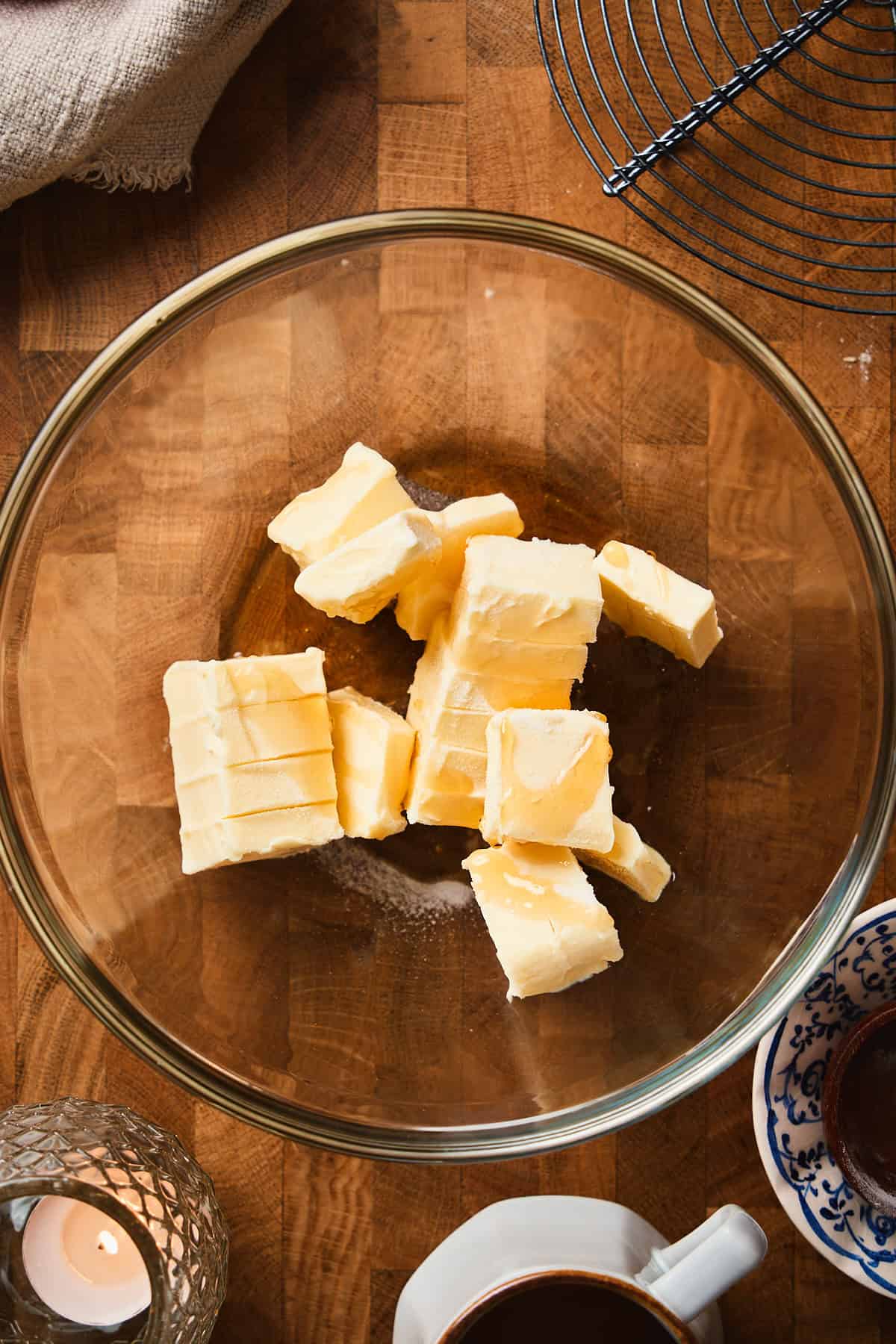 Softened butter chunks with maple syrup added to a glass mixing bowl, ready to whip.