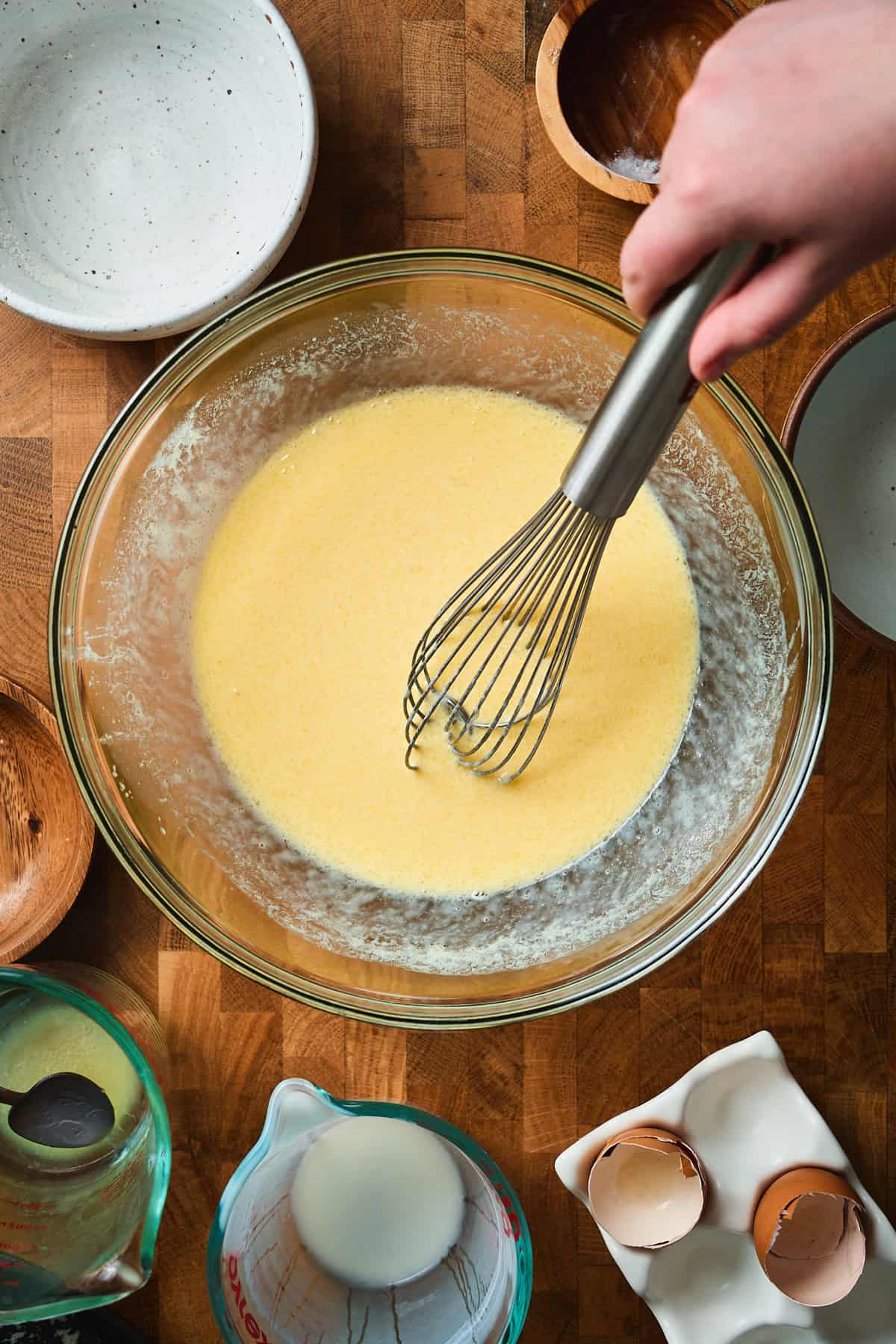 Hand whisking buttermilk, eggs, and butter in a bowl.
