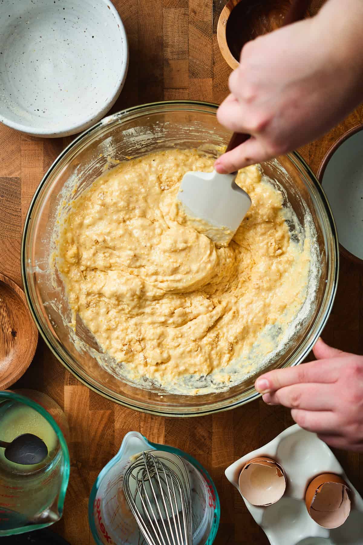 Hand using a rubber spatula to gently combine wet and ingredients to make cornbread batter.