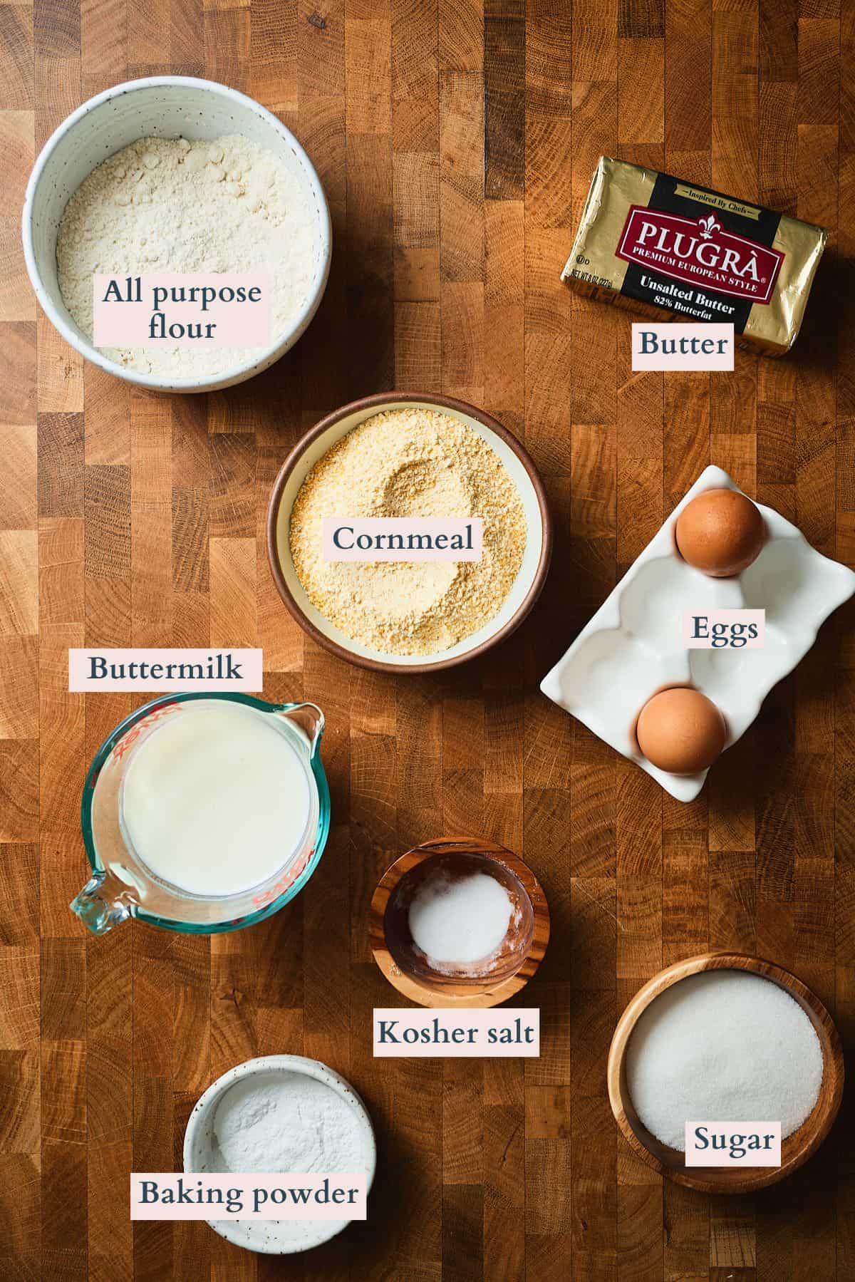 Ingredients to make cast iron cornbread laid out on a table and labeled to denote each ingredient.