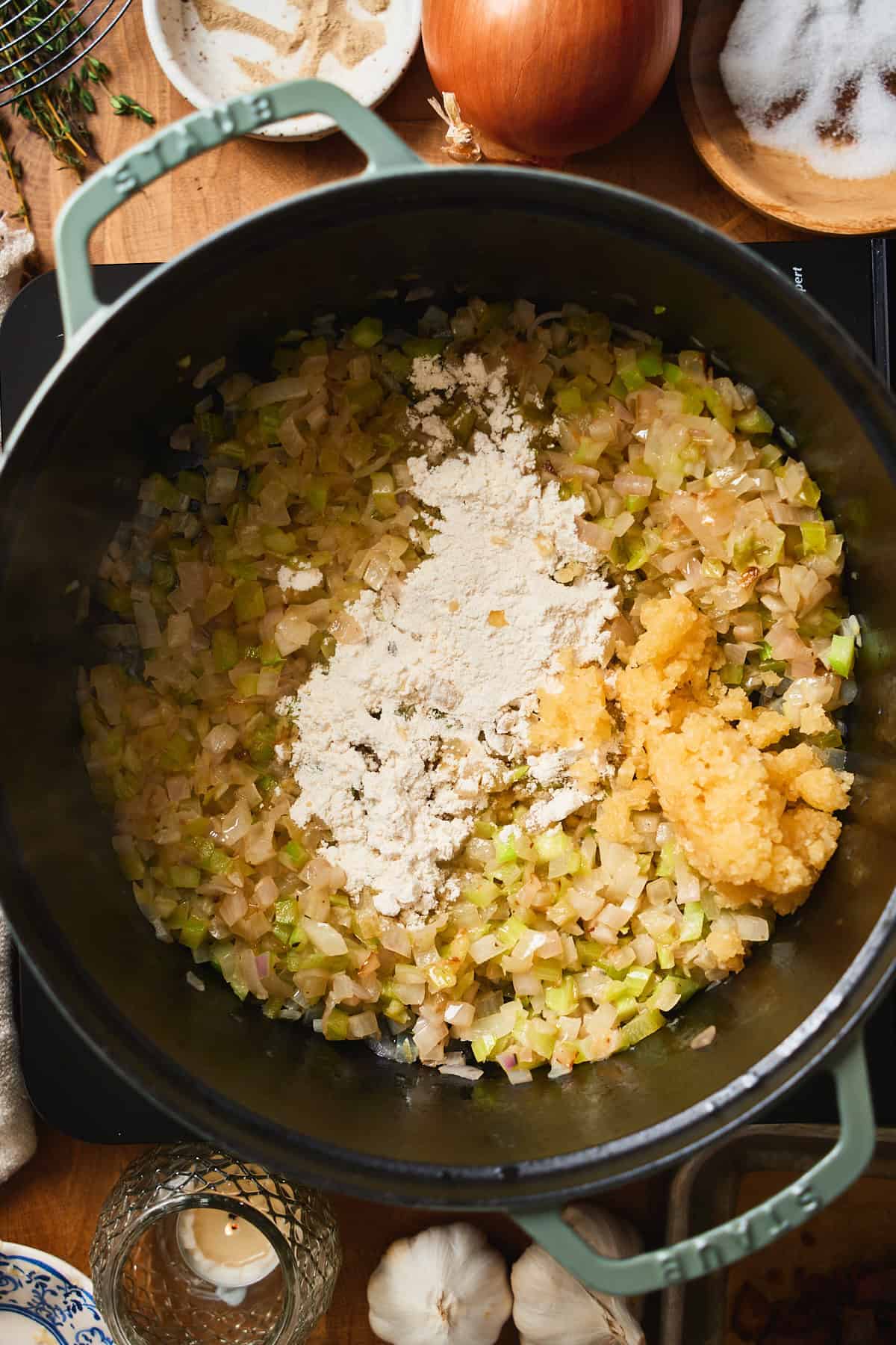 Flour and minced garlic added to sautéed aromatics in a Dutch oven.