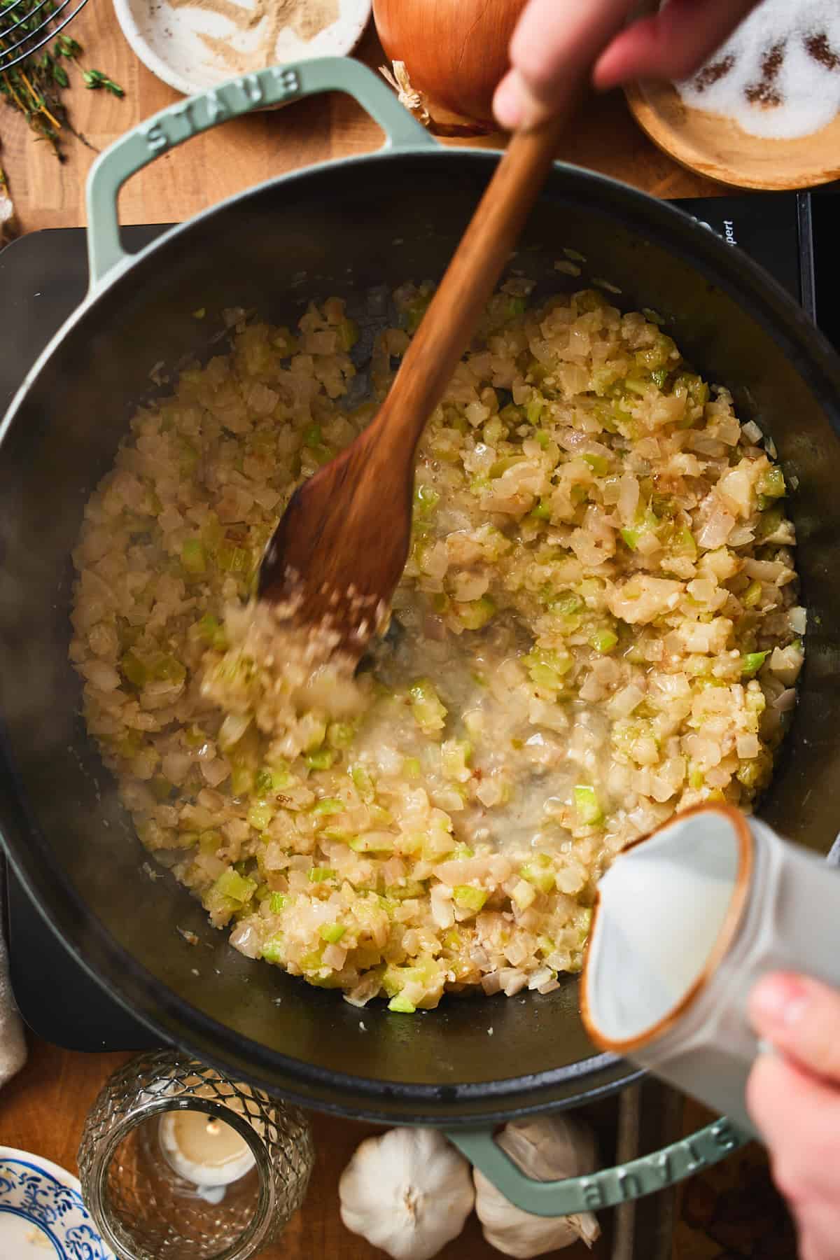 Wine being poured into sautéed aromatics to deglaze the pot.