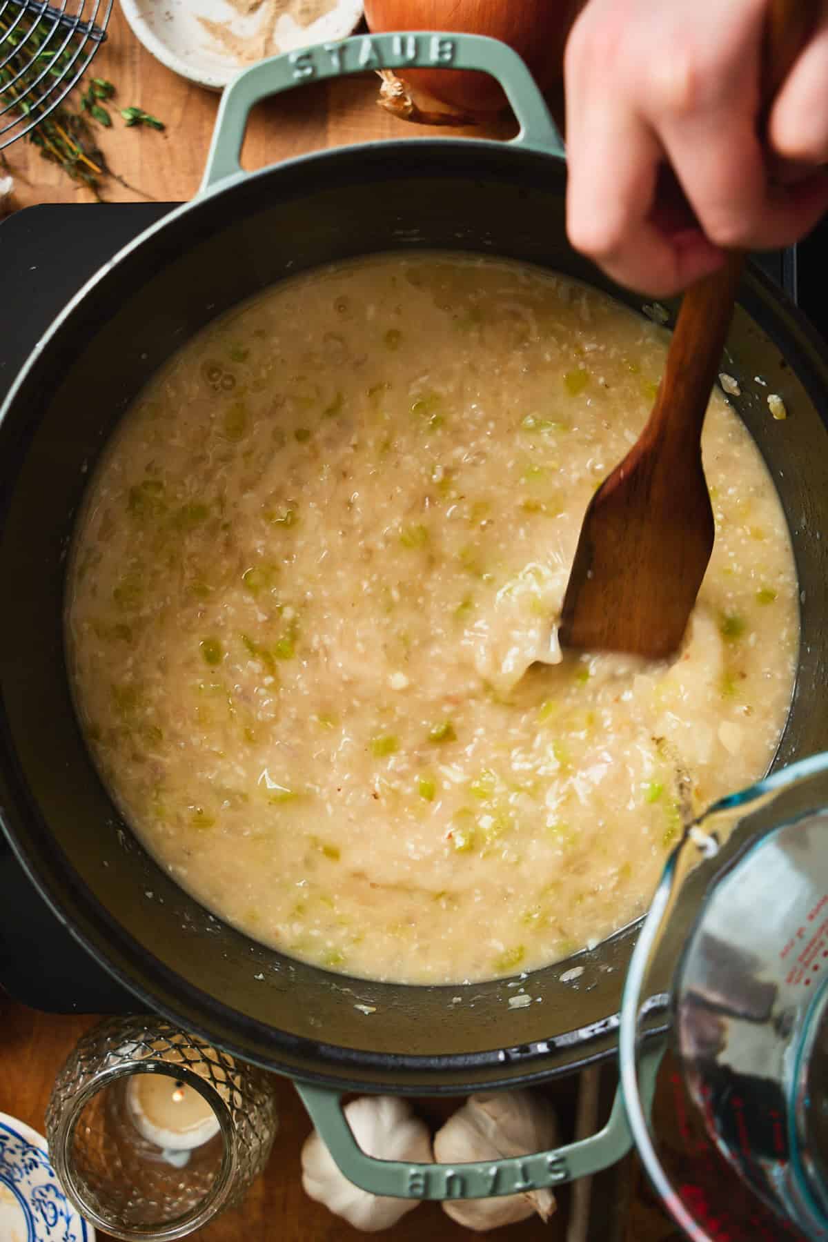 Thick roux paste with aromatics in a Dutch oven, measuring cup nearby.