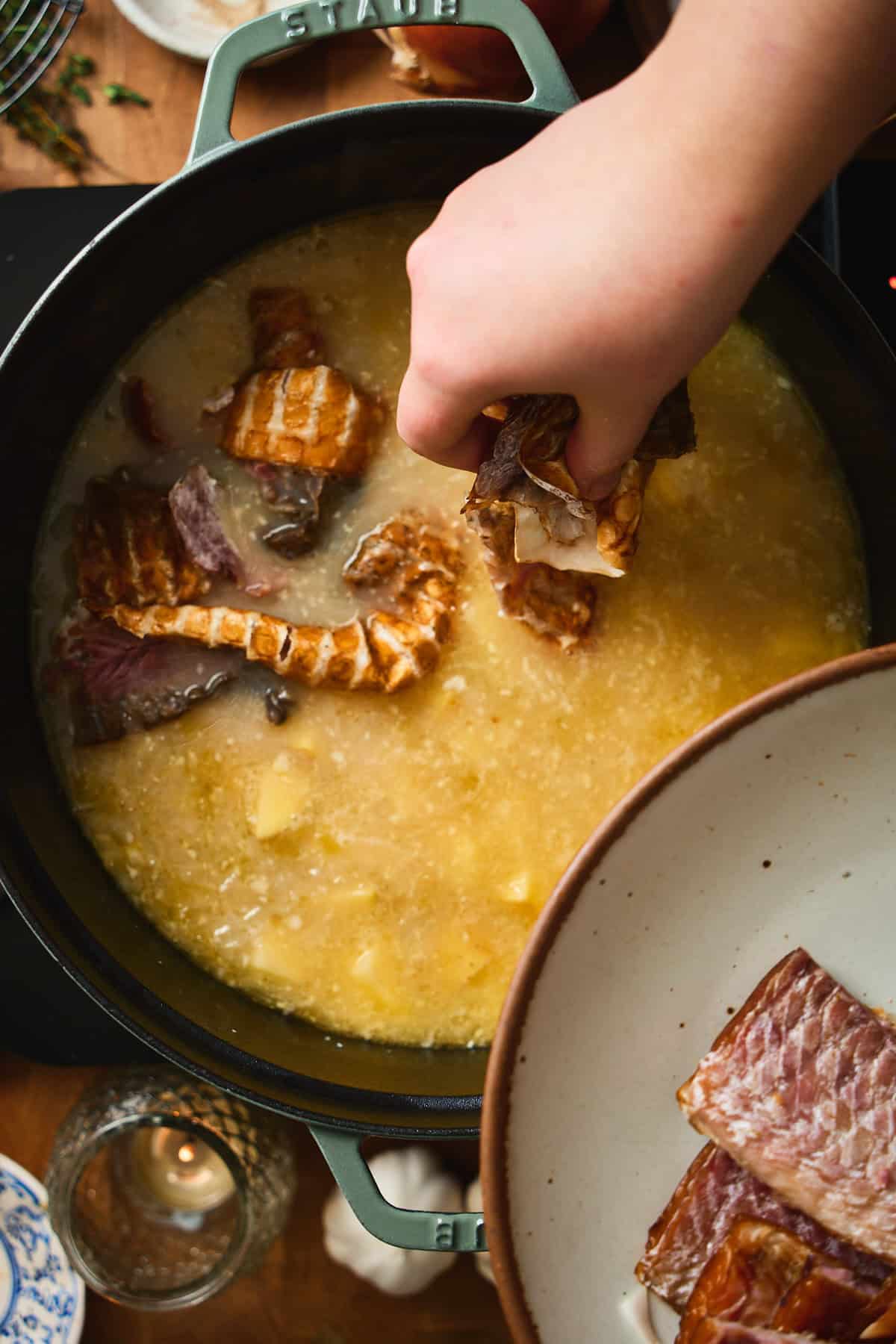 Hand dropping smoked whitefish skin into the simmering chowder base.