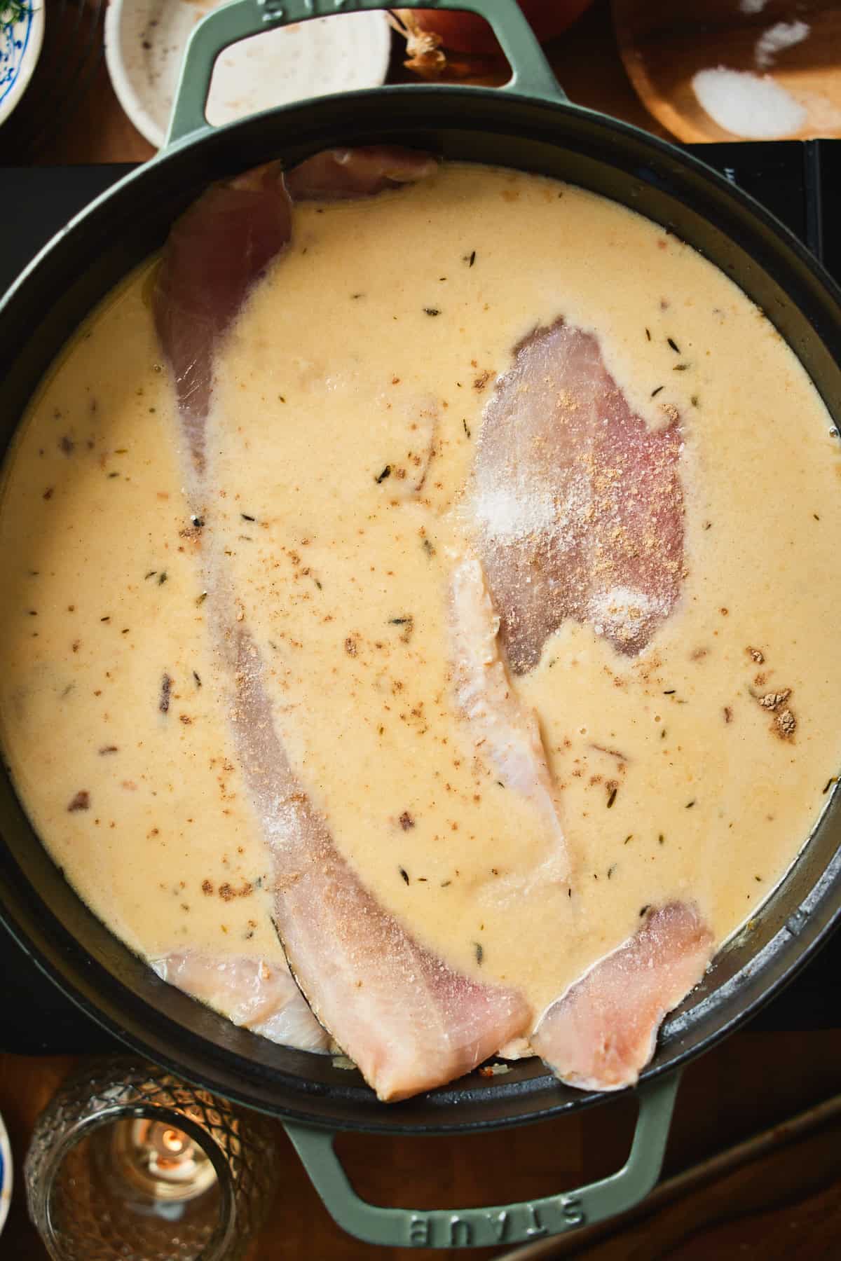 Raw whitefish fillets nestled into the creamy chowder to poach.
