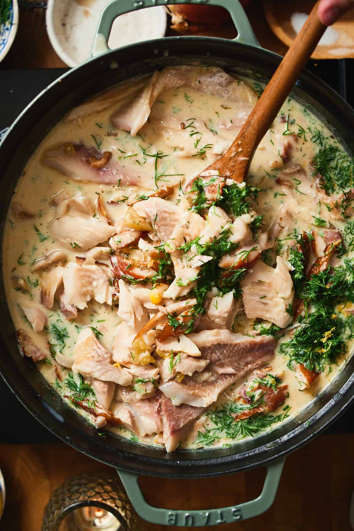 Close-up of whitefish chowder with large fish flakes, smoked whitefish, and fresh dill.