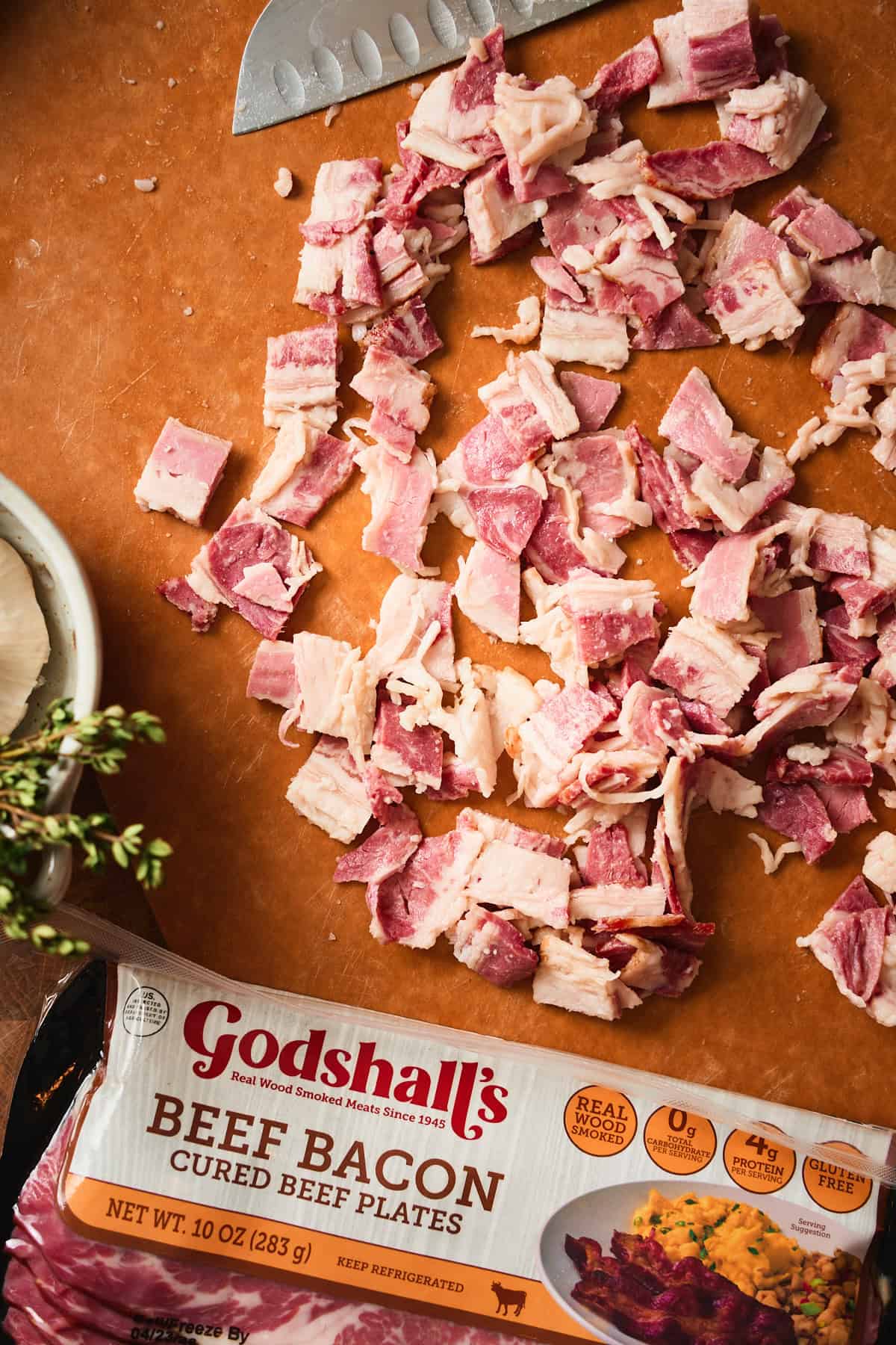 Godshall's beef bacon pieces cut into small pieces on a wood cutting board.