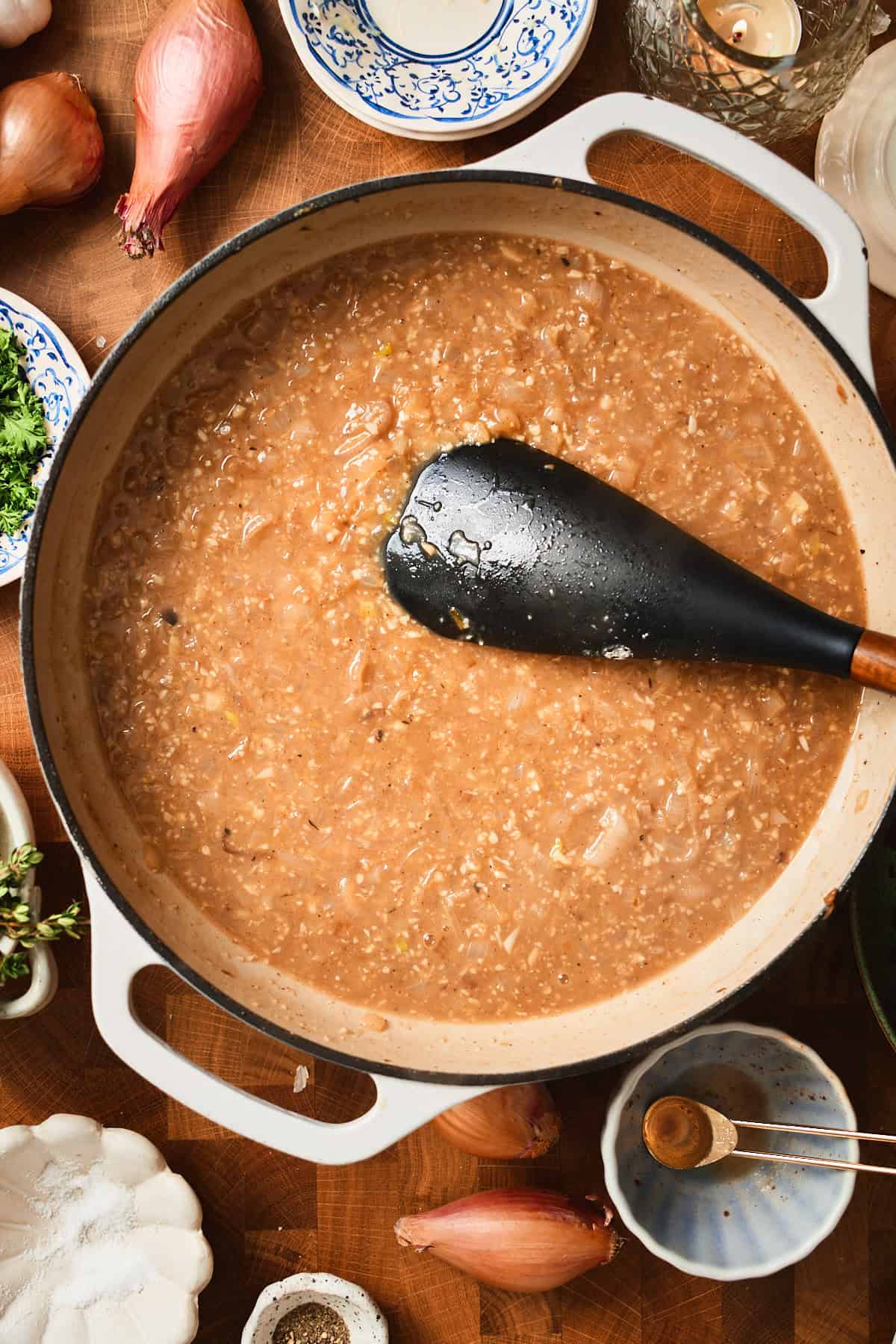 Chicken broth added to a skillet with a roux, onions, and shallots.