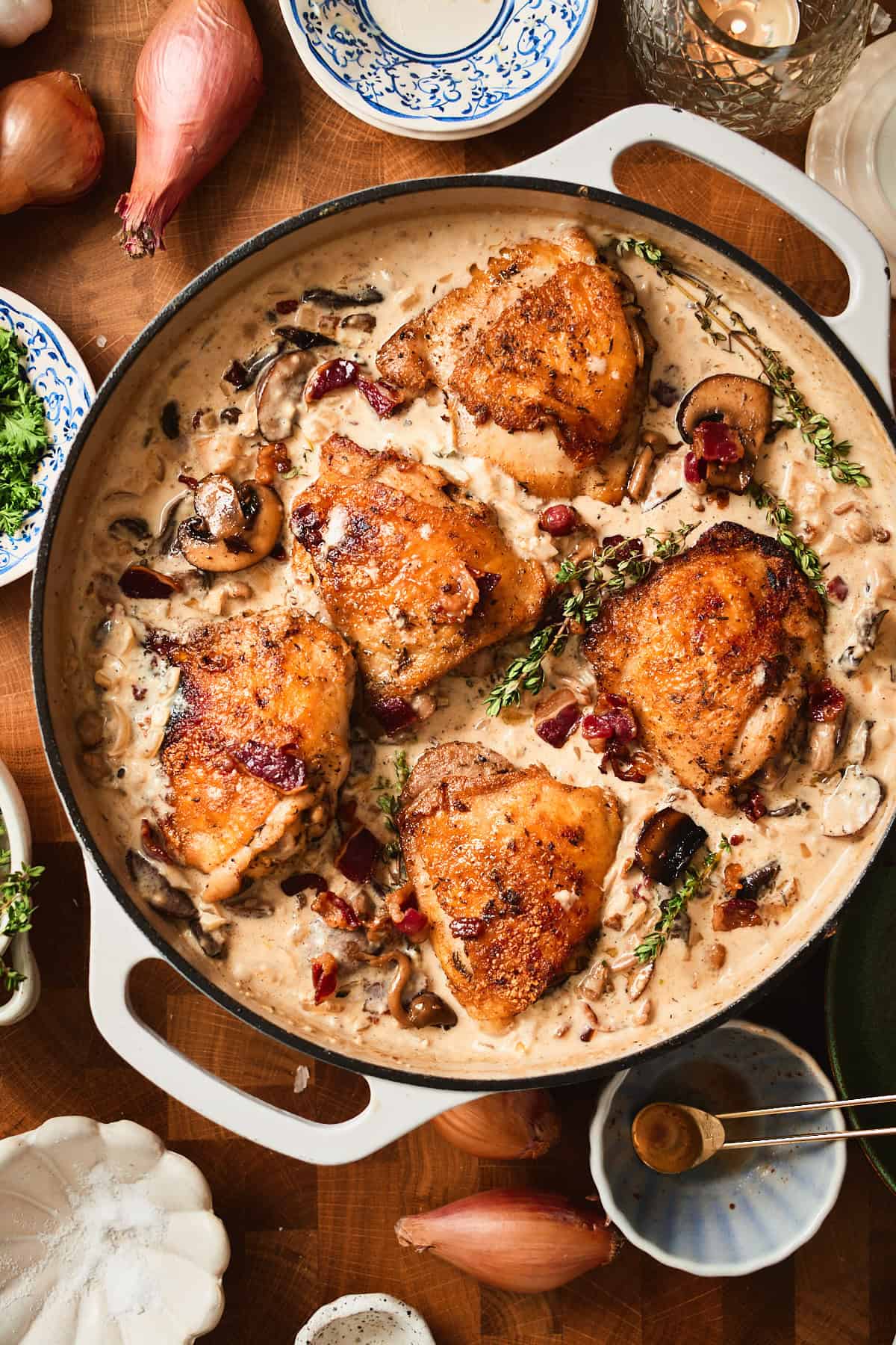 Chicken thighs nested in bacon and mushroom cream sauce with fresh thyme sprigs added.