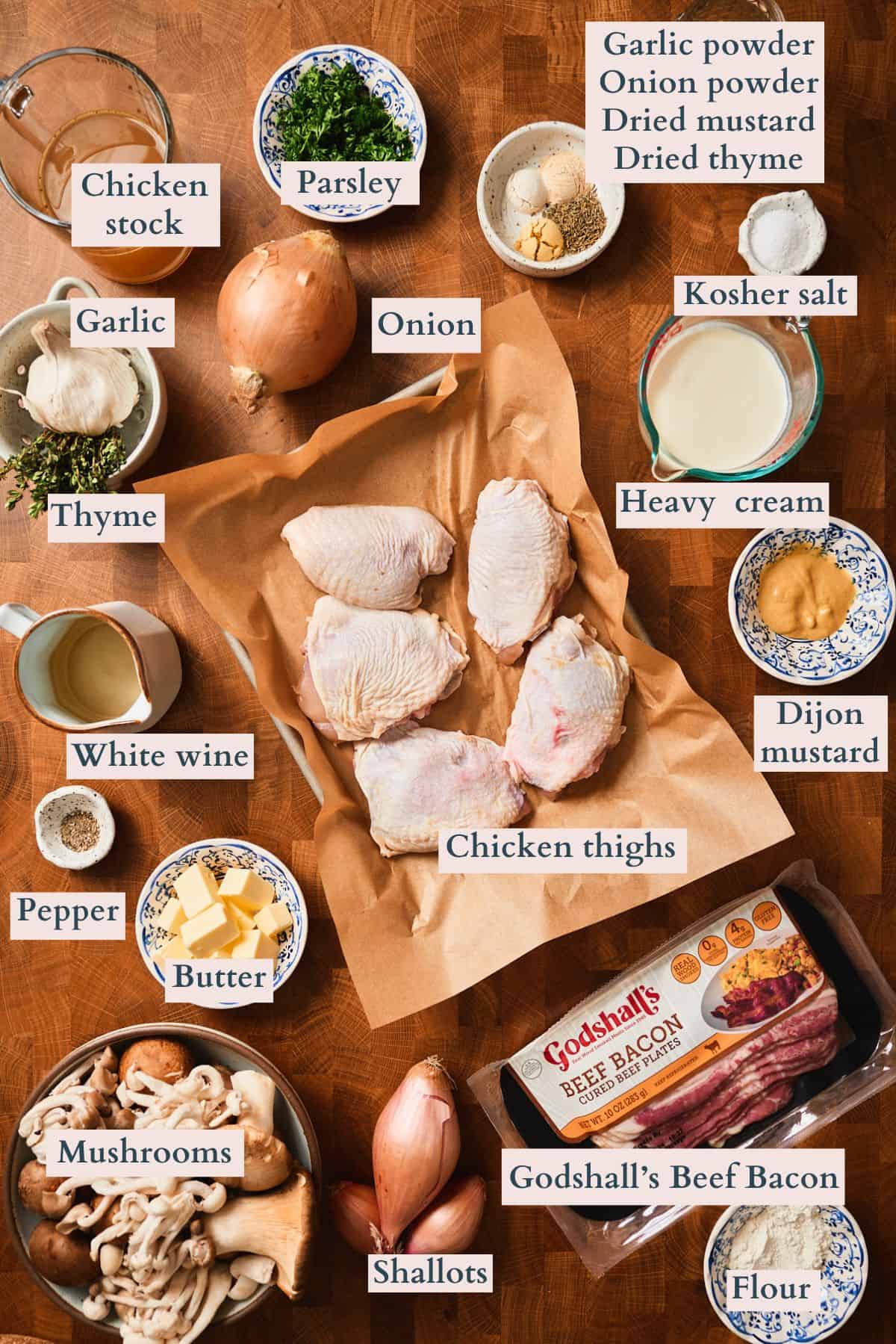 Labeled ingredients for creamy mushroom chicken thighs including chicken thighs, Godshall's beef bacon, mushrooms, heavy cream, and fresh herbs.