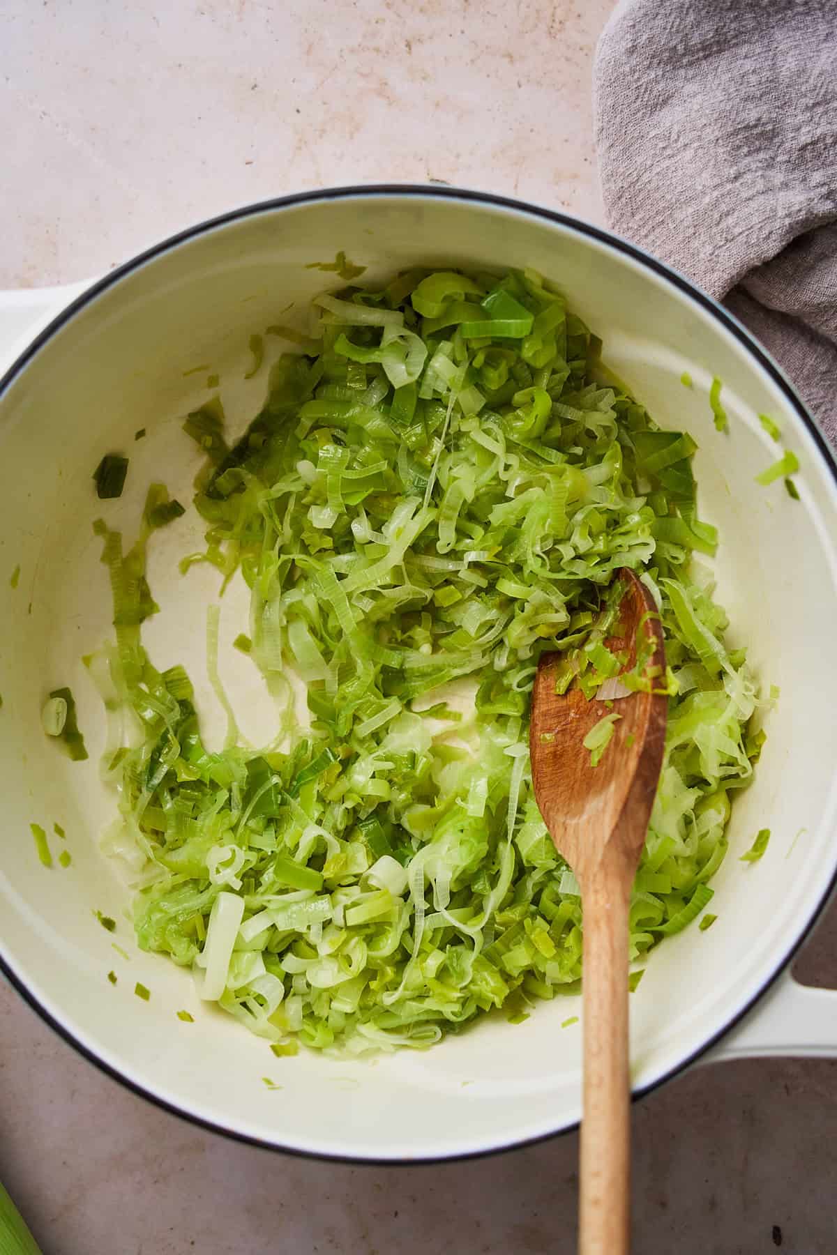 Cooked light and dark green parts of leeks in a Dutch oven.