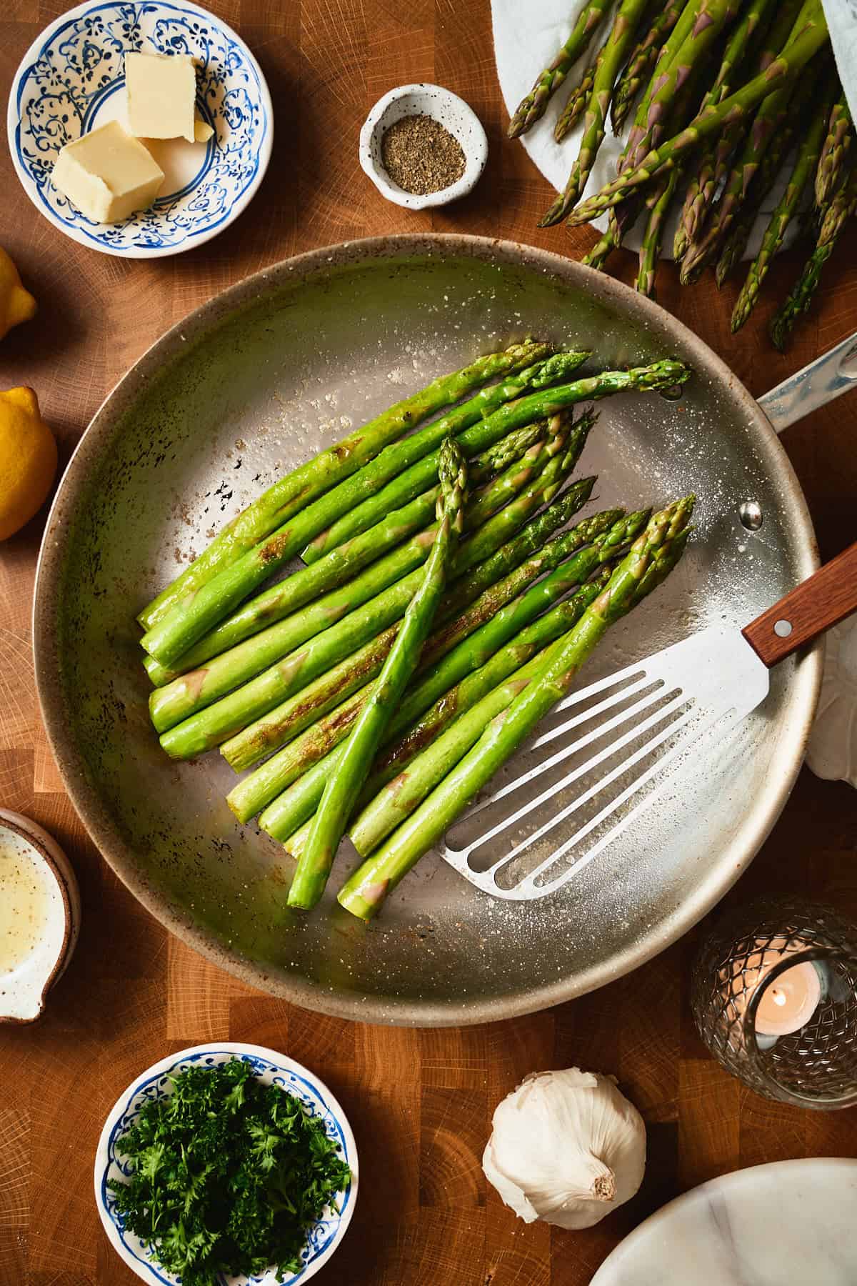 Asparagus sautéing in a skillet with a spatula, golden and tender-crisp.