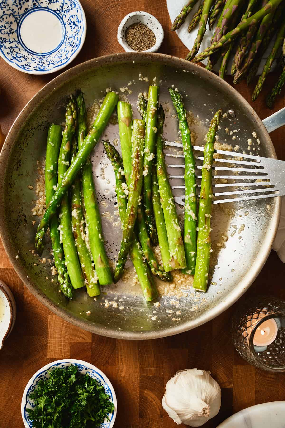Cooked asparagus in a pan with garlic and lemon juice added.