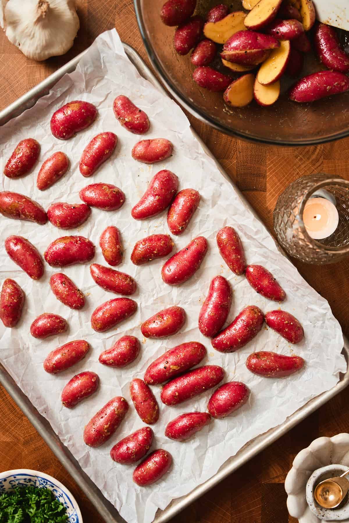 Baby red potatoes cut side down on a baking sheet with a candle nearby.