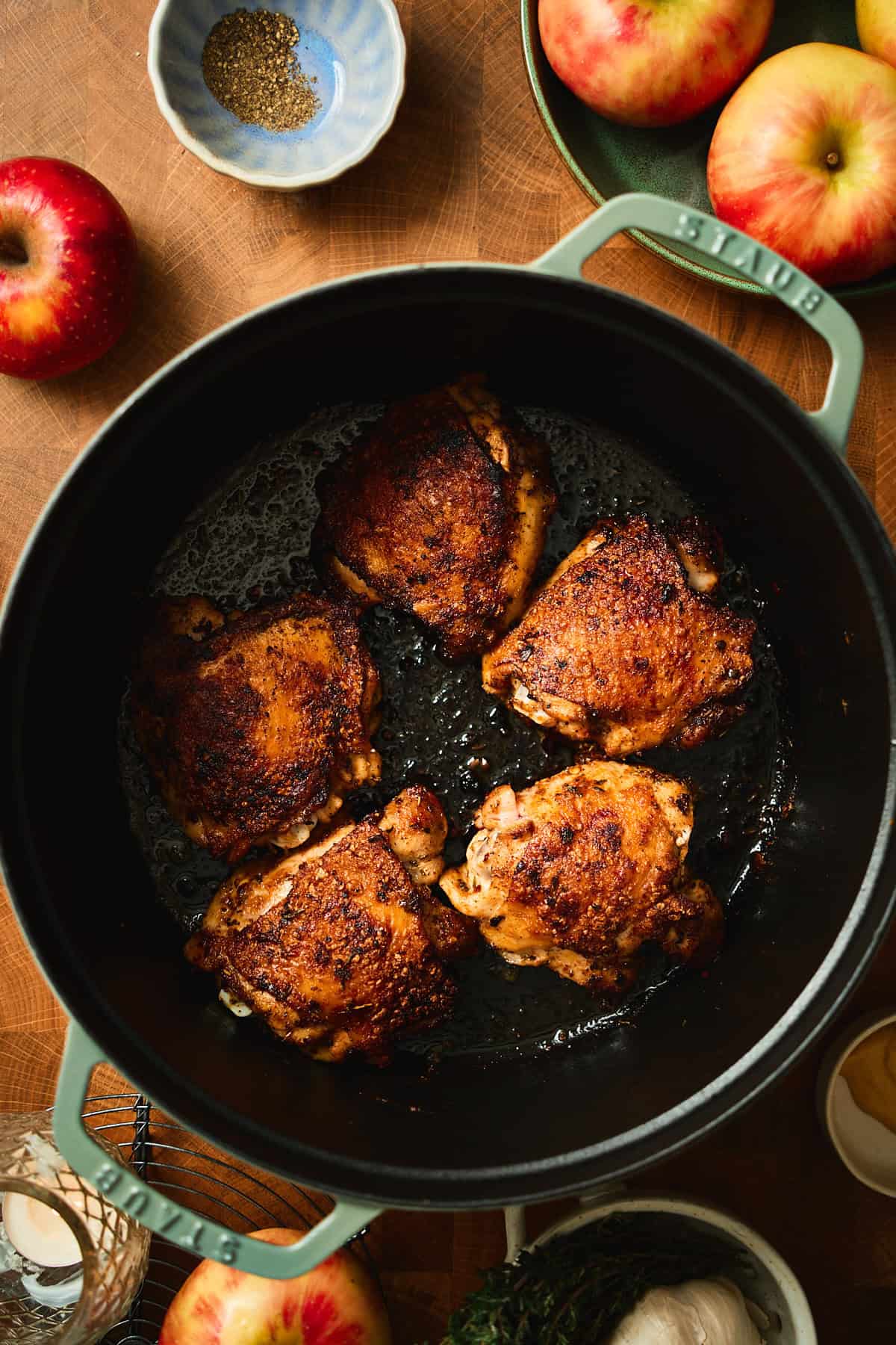 Five golden-brown seared chicken thighs in a Staub Dutch oven.
