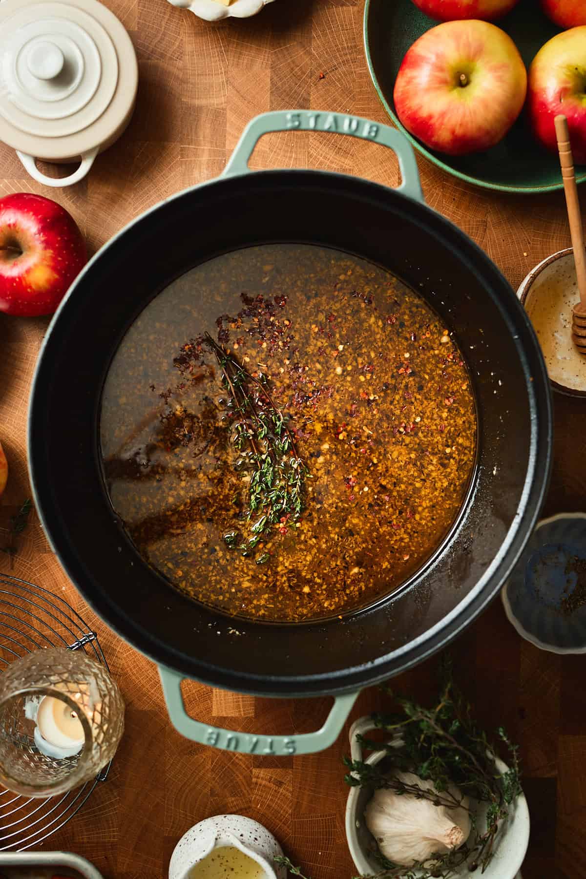 Apple cider glaze coming together in a Dutch oven with thyme added.
