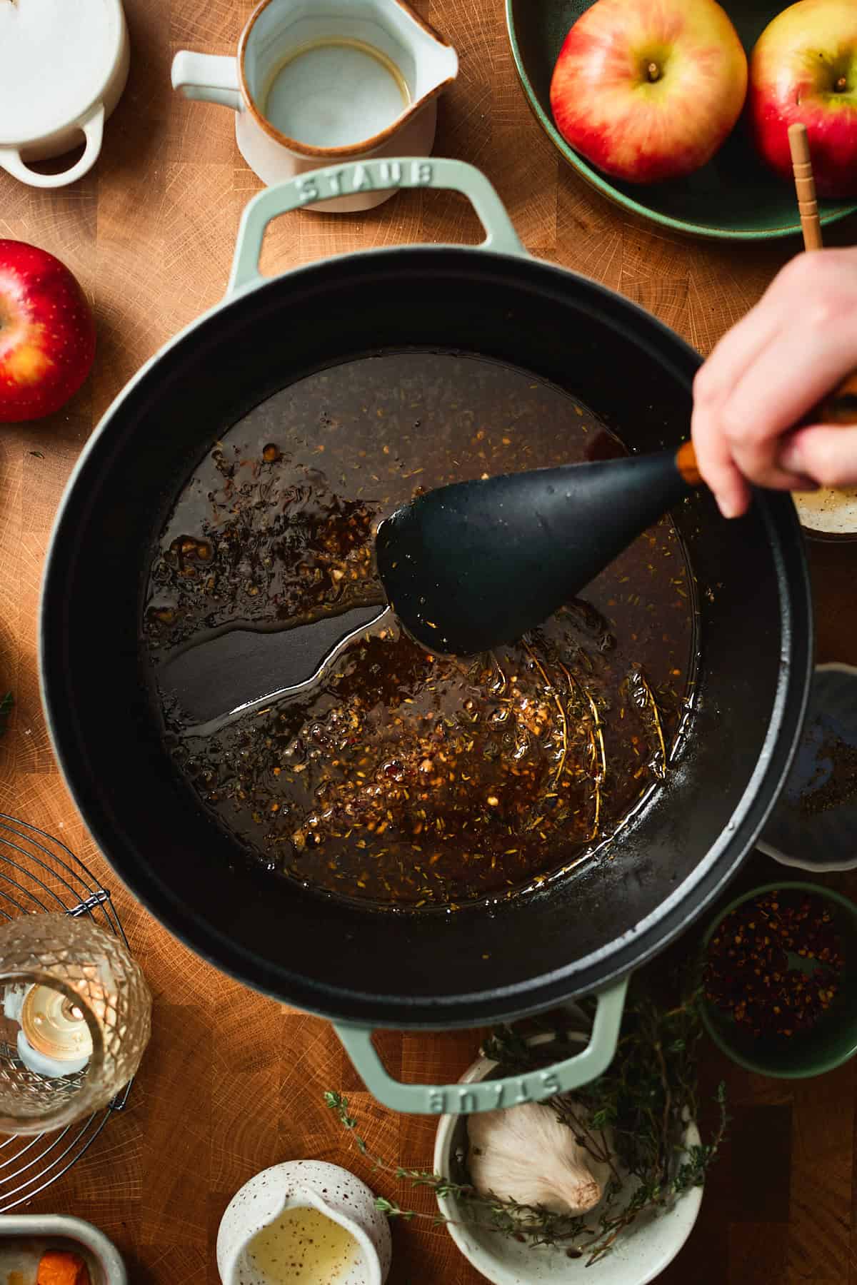 Hand dragging apple cider glaze on the bottom of a Dutch oven.