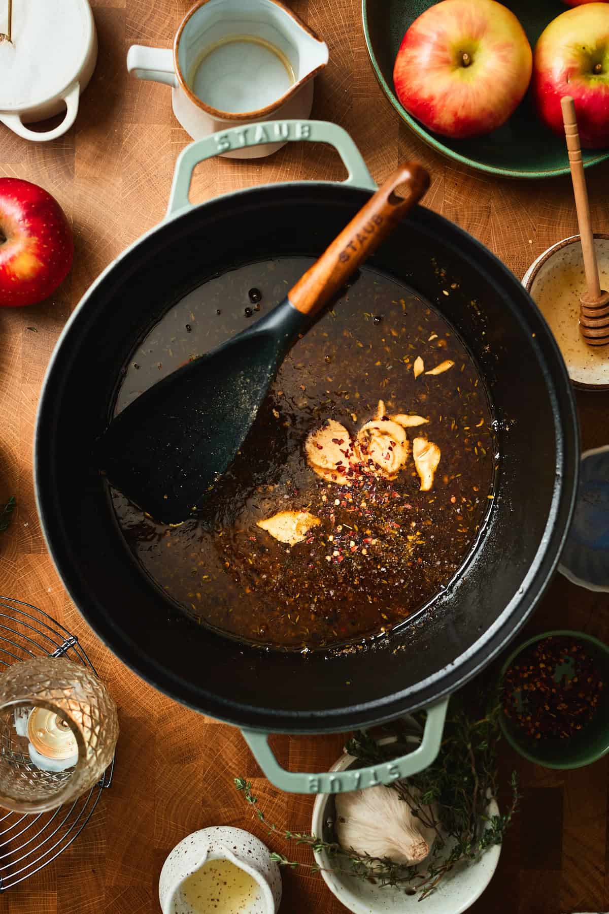 Dijon mustard and red pepper flakes added to a Dutch oven with apple cider glaze.