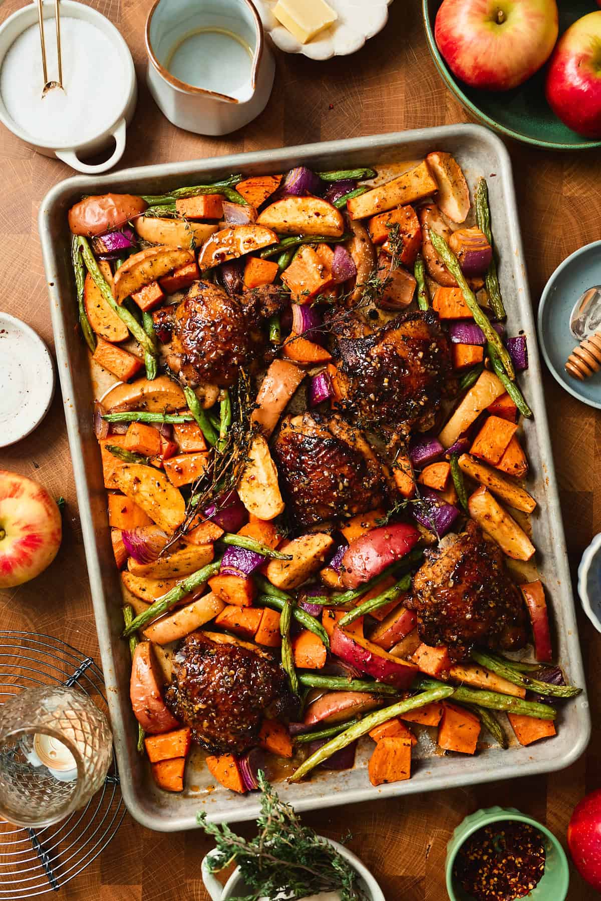 Glaze added to the top of chicken thighs with vegetables getting ready to roast in the oven.