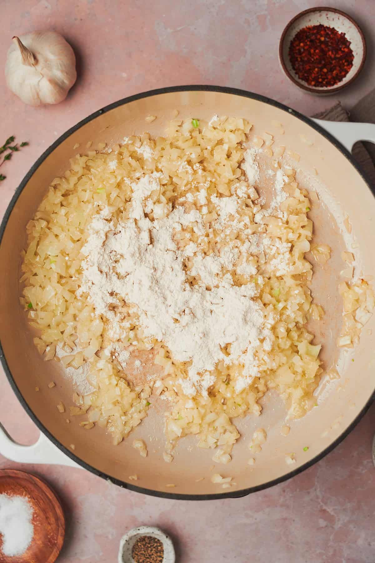 onions being cooked in butter with flour sprinkled in an enameled skillet.