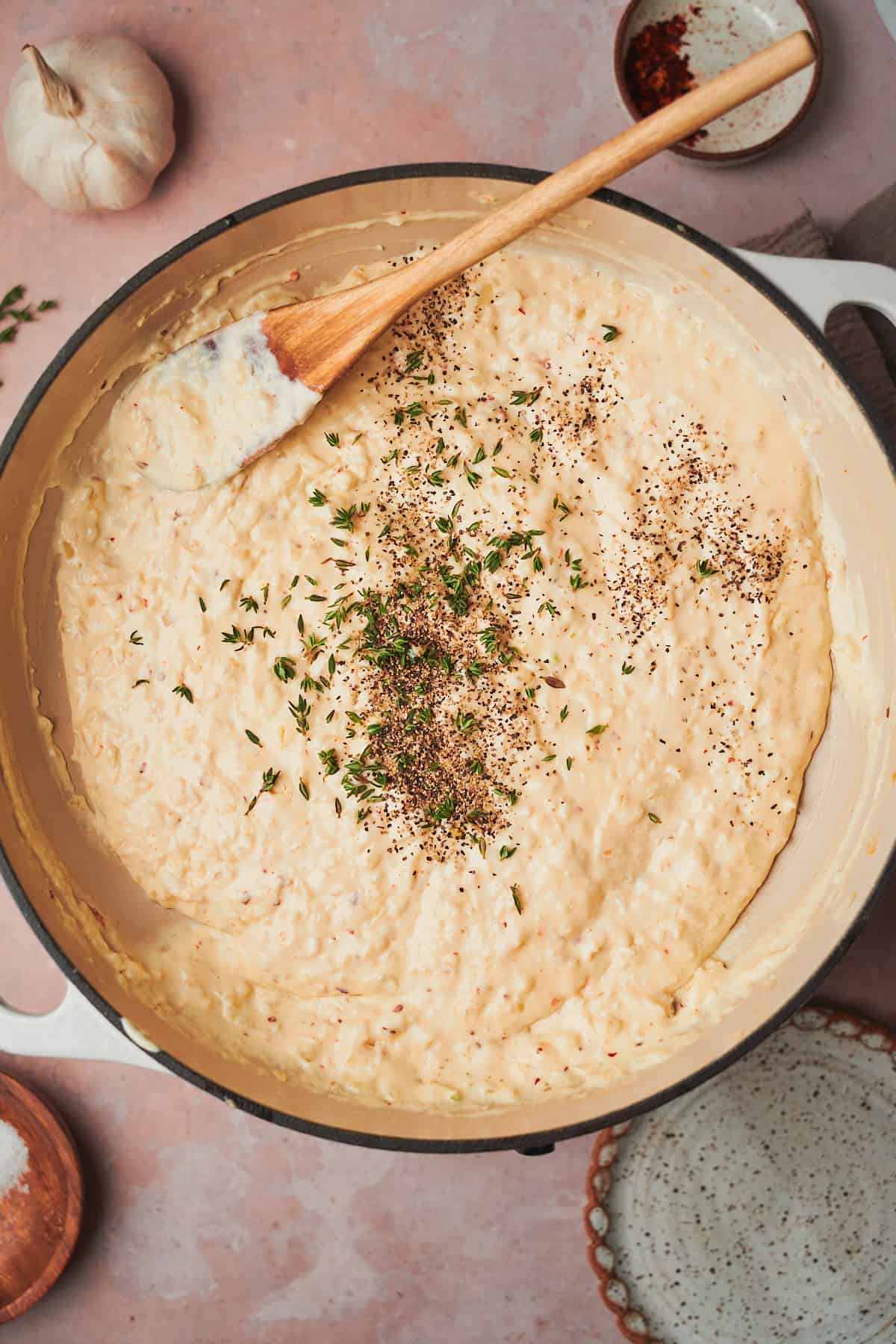 creamy sauce beginning to come together in a skillet with black pepper and fresh thyme added to the mixture.