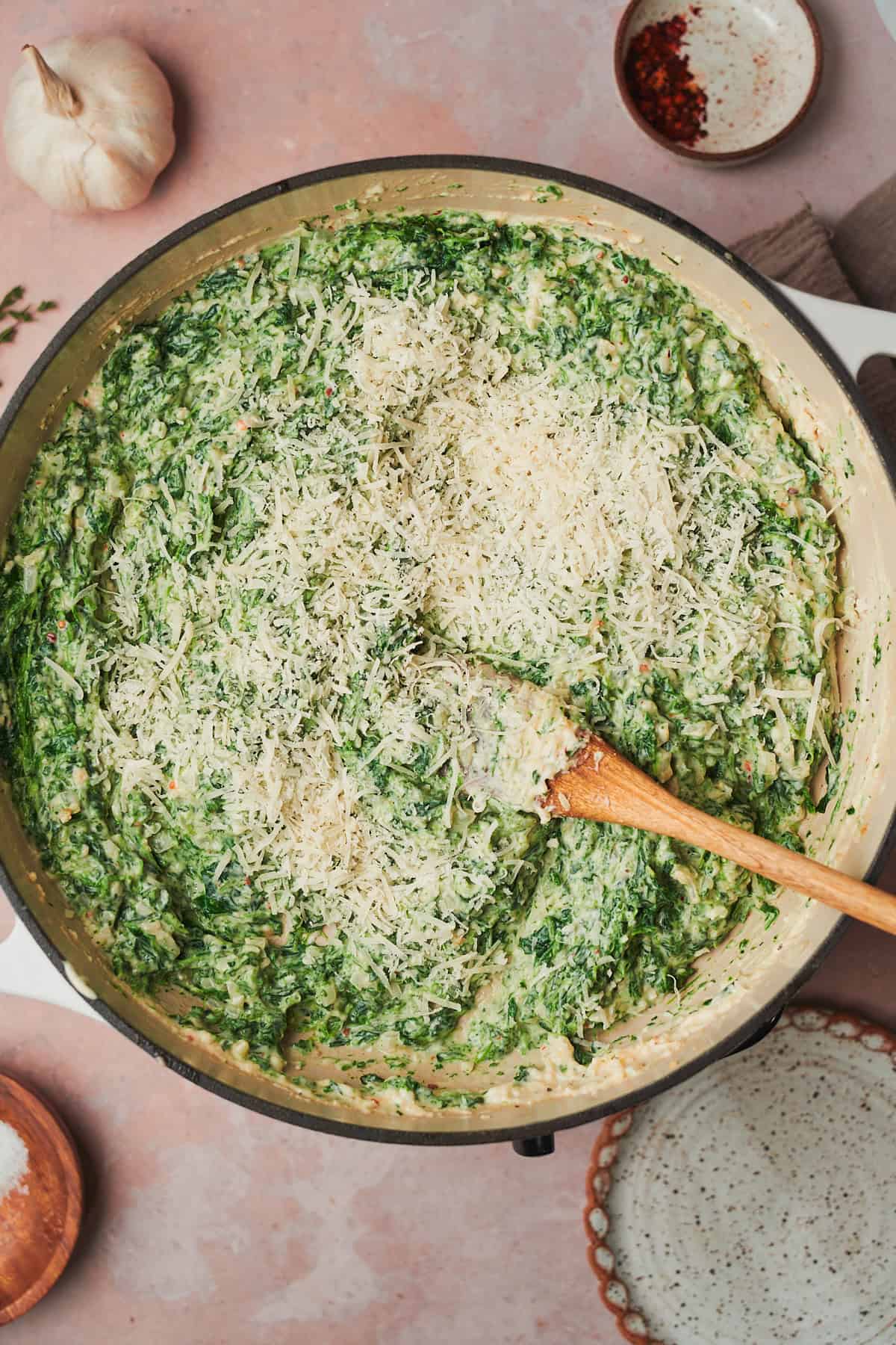 bright cream creamed spinach in a skillet with shredded parmesan cheese added to it.