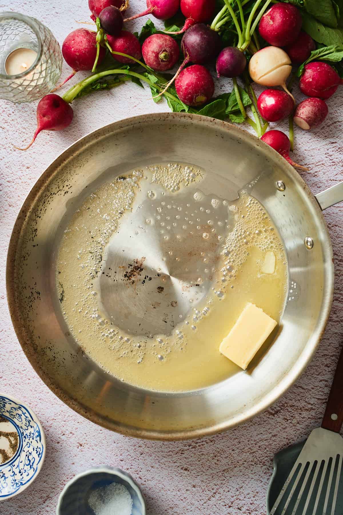 Pat of butter beginning to melt in a stainless skillet, just starting to foam.