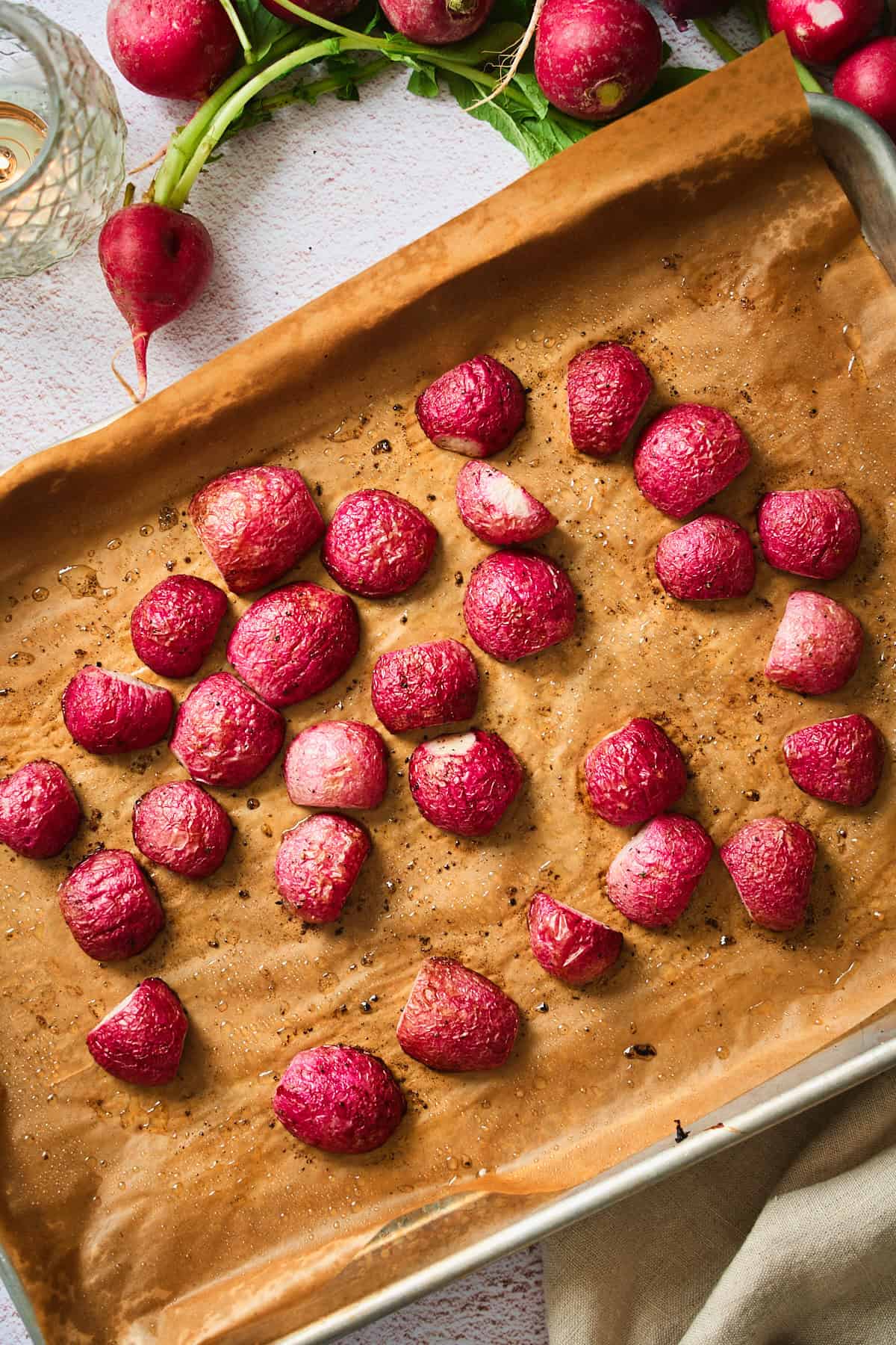 Roasted radishes on a parchment-lined baking sheet, caramelized and wrinkled after roasting.