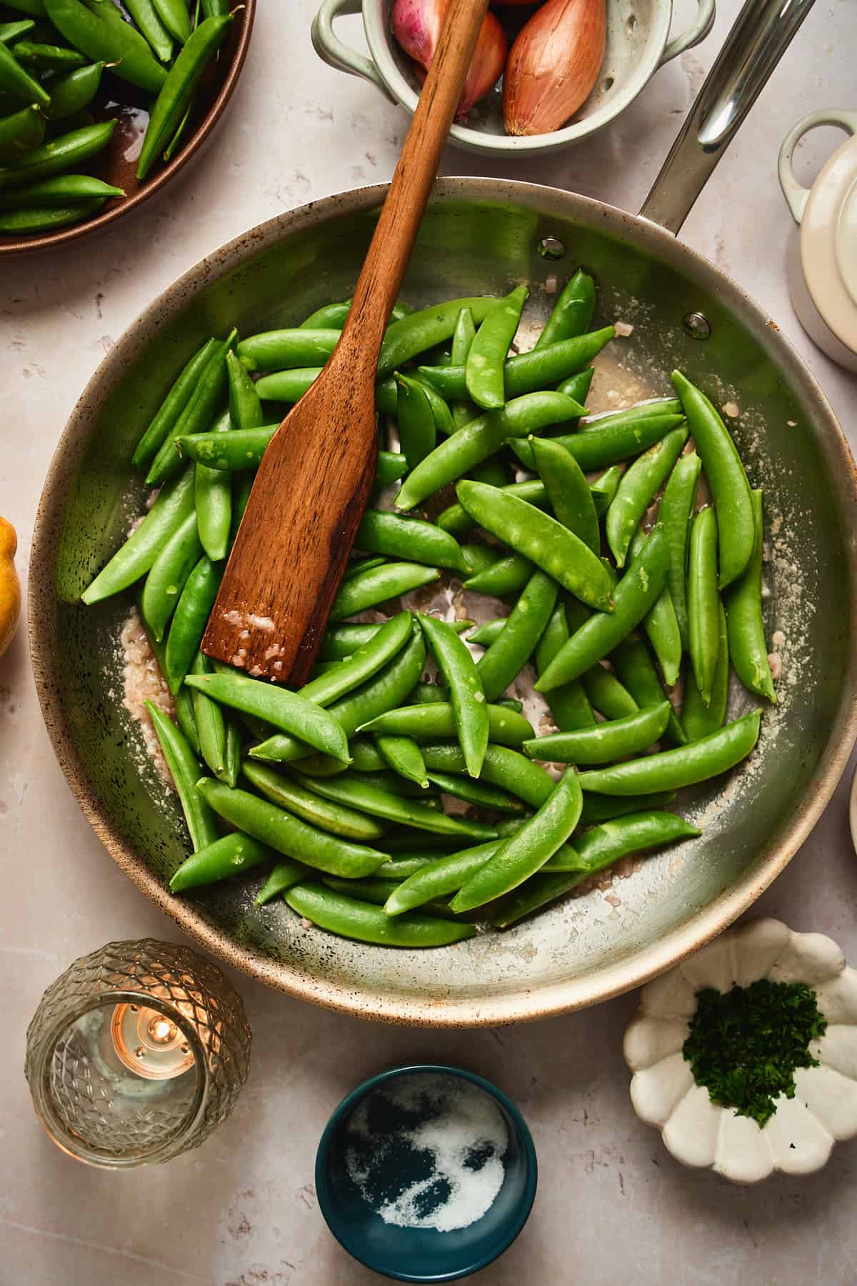 Fresh snap peas just added to a skillet with melted butter and shallots.