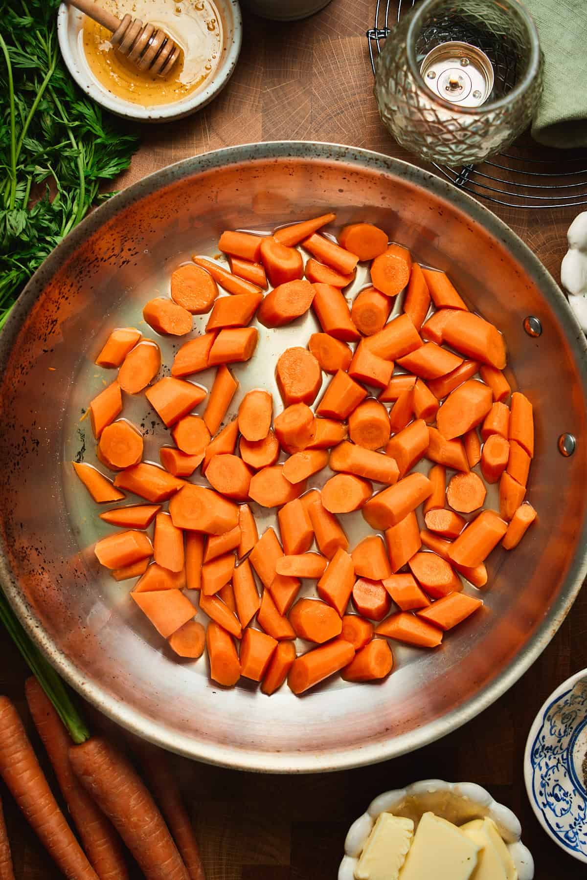 Overhead of steamed carrots in a skillet with water almost fully evaporated.