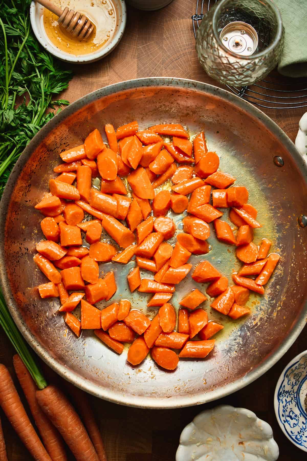 arrots coated in melted butter in a skillet, glossy and just starting to caramelize.
