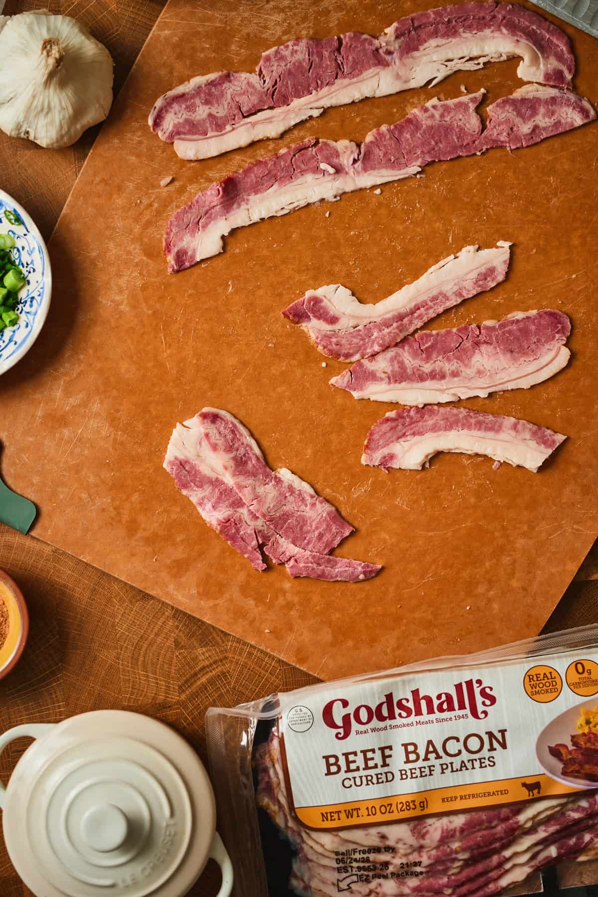 Beef bacon strips cut into quarter-piece sections on a wooden cutting board.