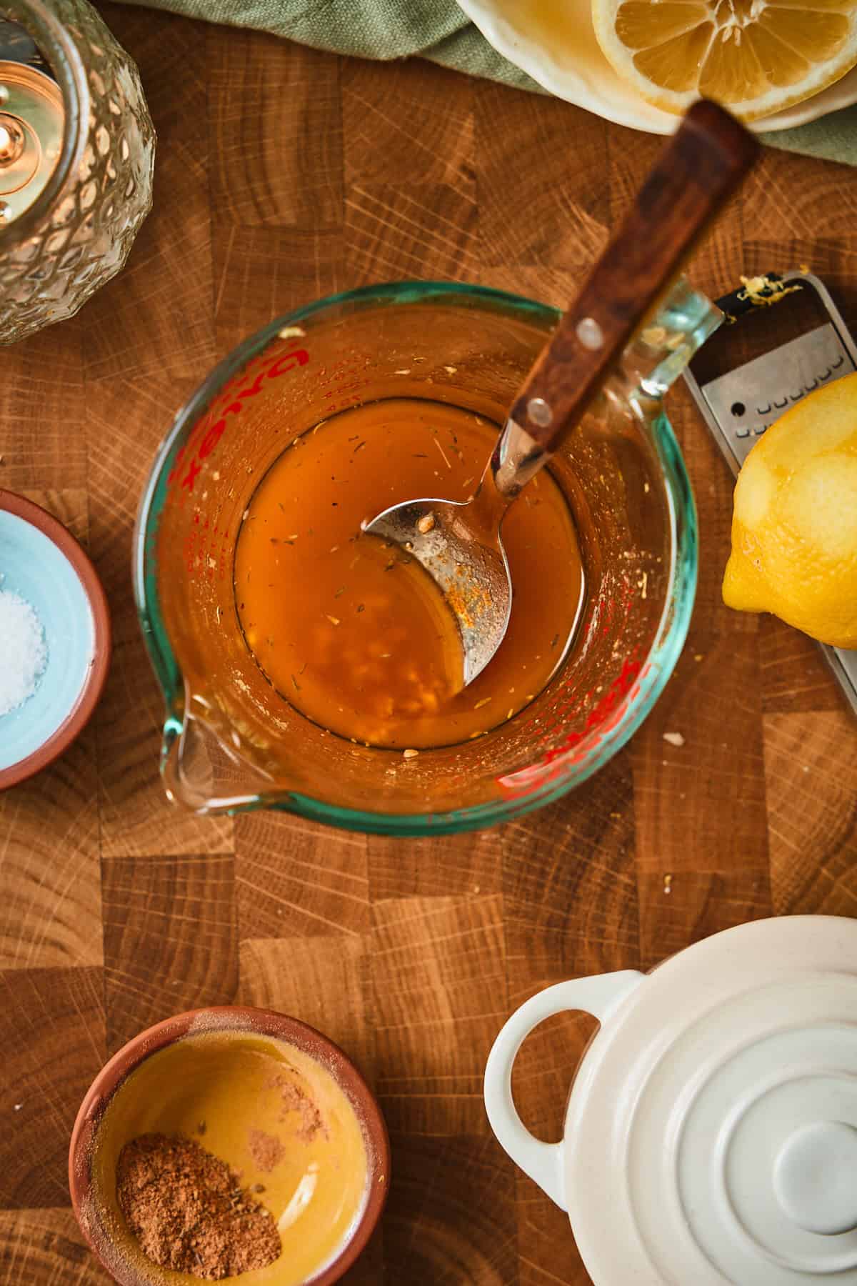 Cajun butter brush ingredients whisked together in a glass measuring cup with lemon zest and seasoning visible.