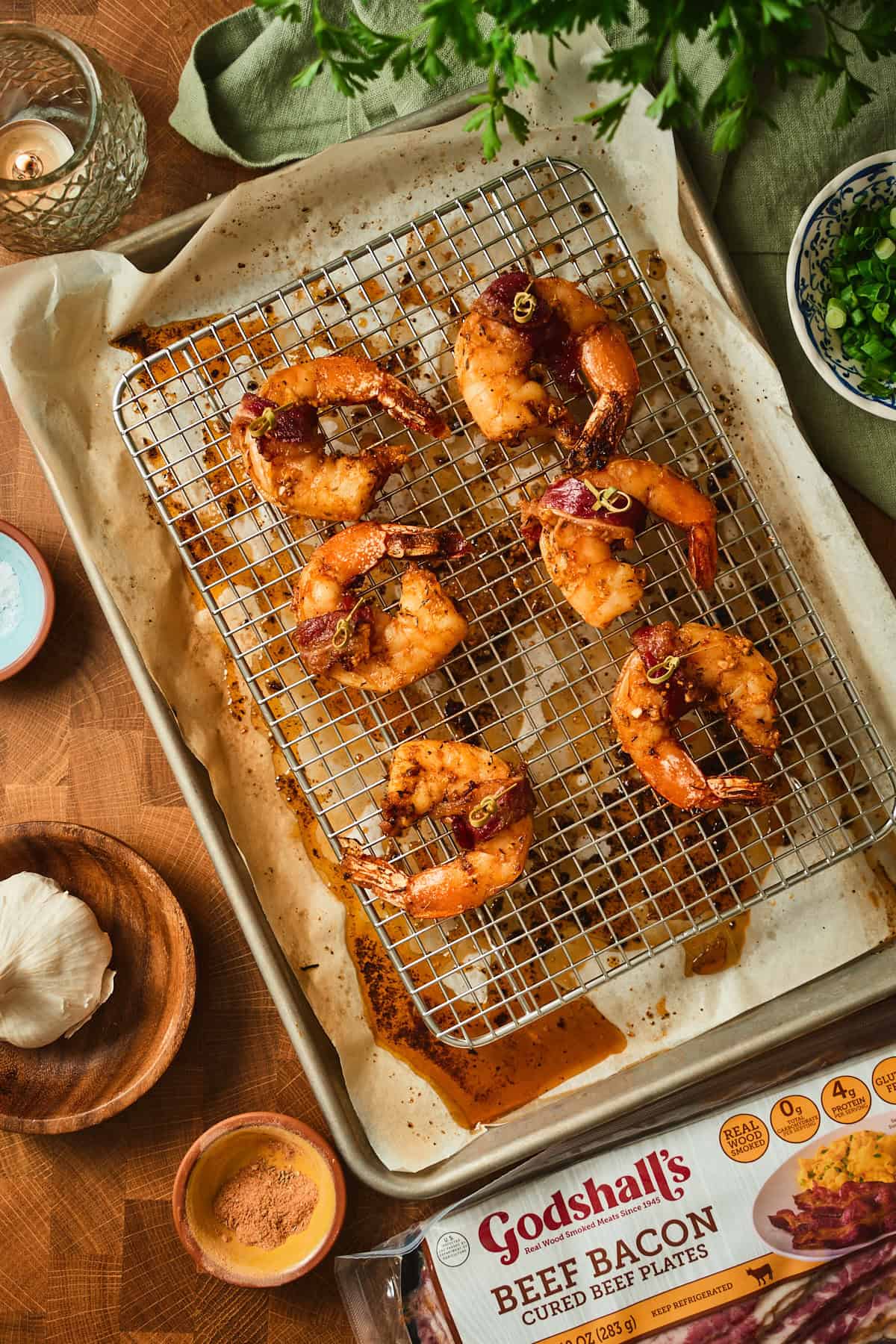 Oven baked bacon wrapped shrimp on a wire rack, bacon bronzed and glossy with Cajun butter drippings.