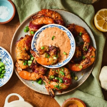 Cajun beef bacon wrapped shrimp on a plate with a bowl of remoulade.