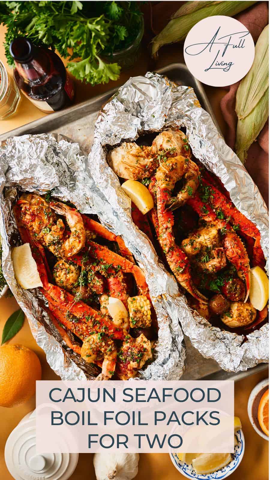 Two open foil packets of Cajun seafood boil with snow crab, shrimp, corn, and potatoes in garlic butter sauce, with corn husks, parsley, beer, and citrus styled around the sheet pan. Text overlay reads "Cajun Seafood Boil Foil Packs for Two."