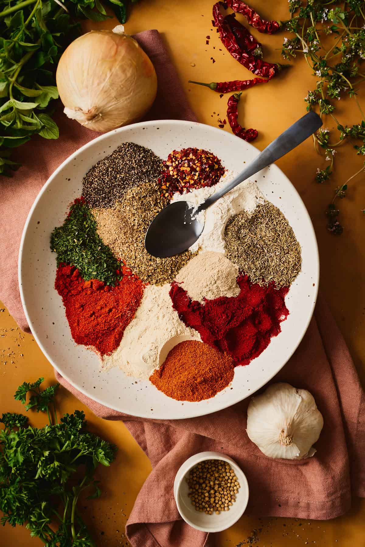 All the seasoning spices measured into separate piles in a speckled bowl, a spoon resting on top.