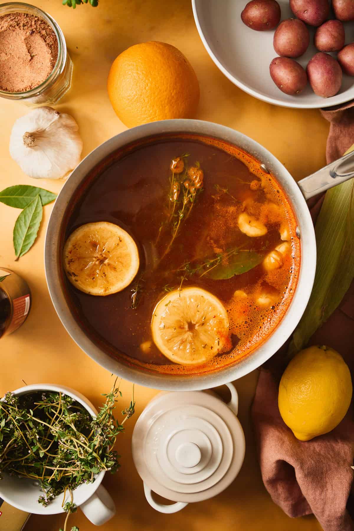 Lemon, thyme, garlic, bay leaves, and seasoning in a small pot coming together to make a flavorful broth.