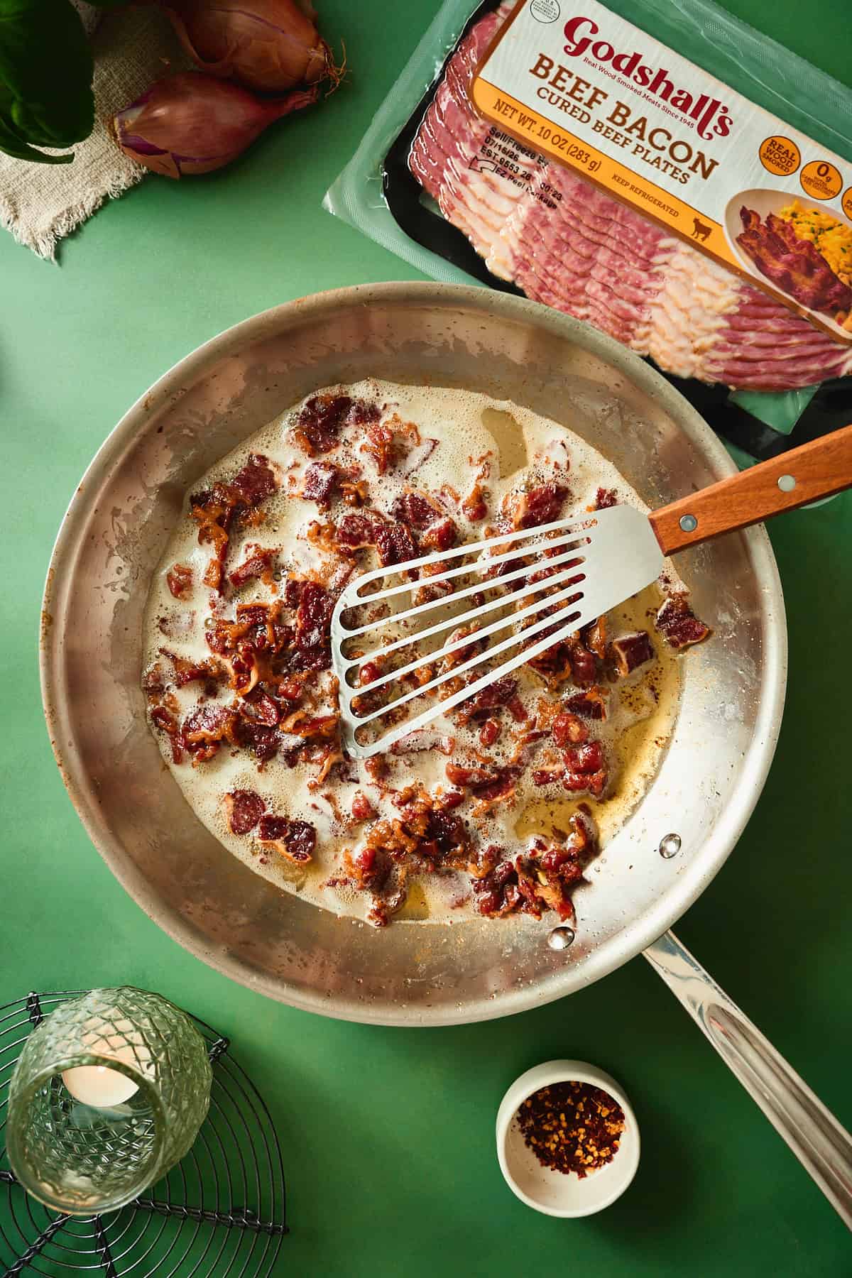 Beef bacon pieces rendered until crispy in a skillet for blistered tomato pasta.