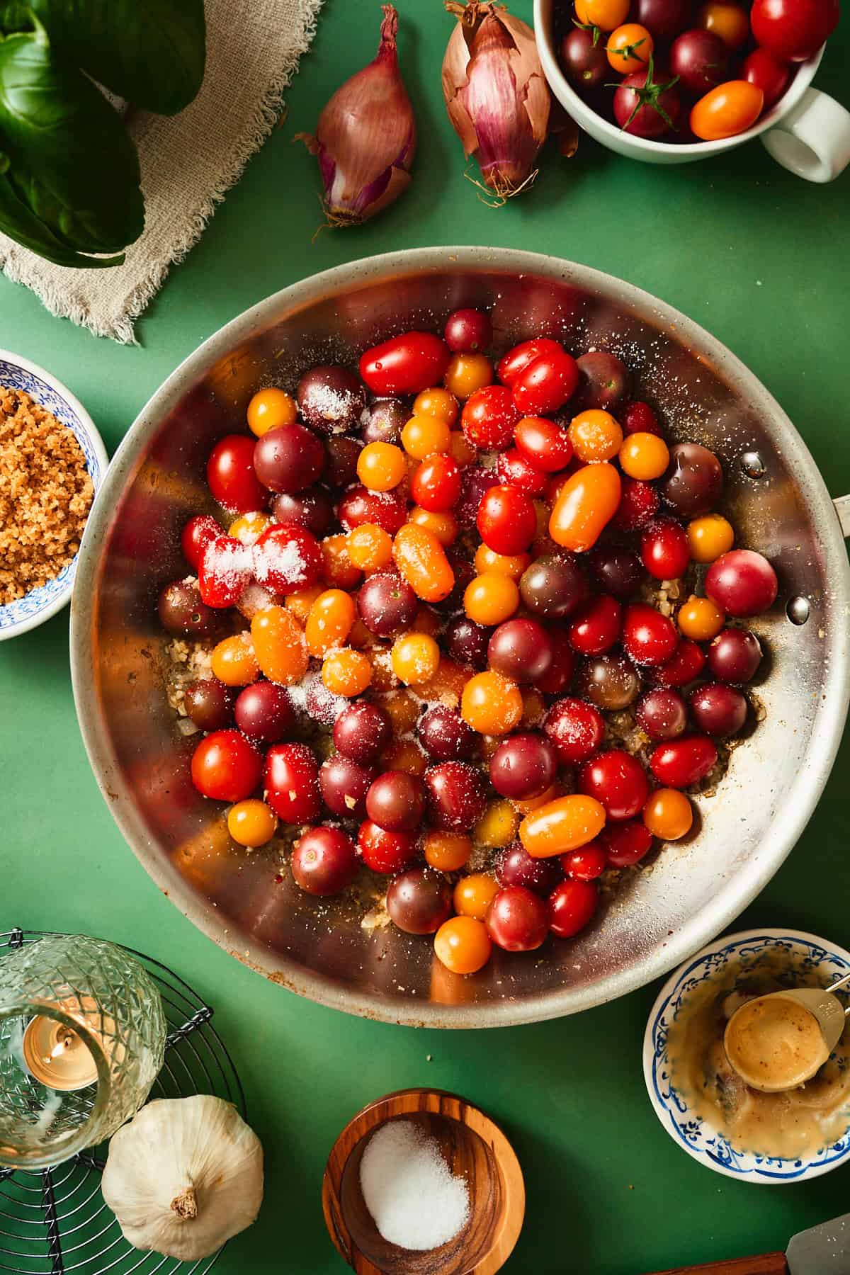 Whole cherry tomatoes added to the skillet with salt to cook for tomato bacon pasta.