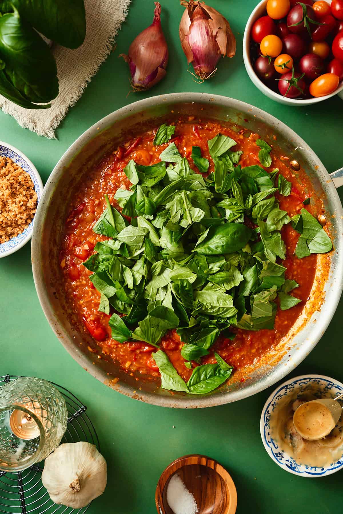 Torn fresh basil added to the tomato sauce in a skillet for tomato bacon pasta.