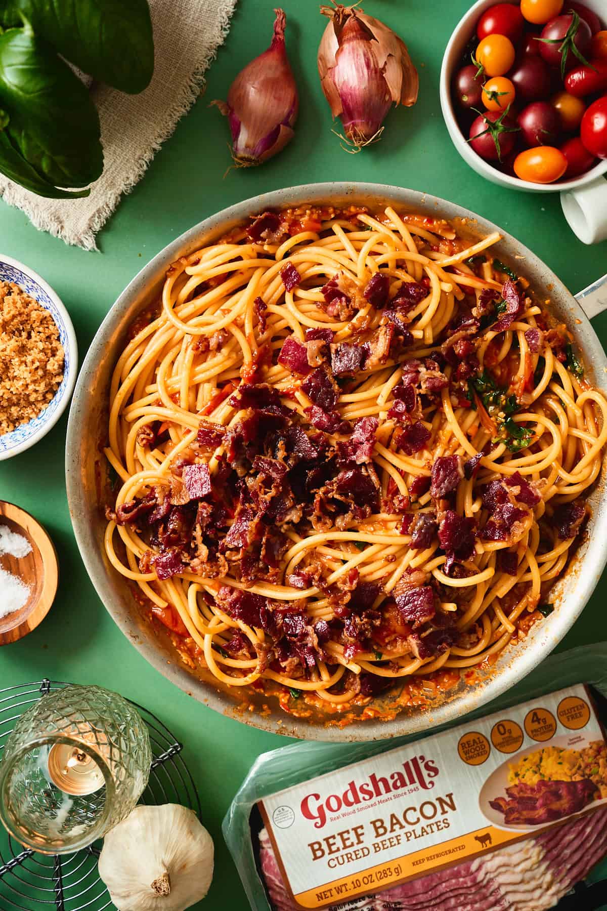 Tomato pasta with bucatini and crispy beef bacon in a skillet.
