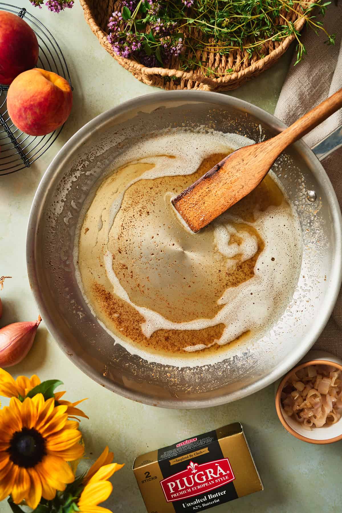 Browned butter foaming golden with toasted milk solids in a stainless skillet.
